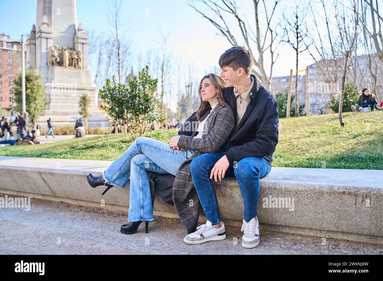 Ein junges Paar sitzt auf einer Bank in der Stadt. Ein Paar umarmt und ruht sich aus. Stockfoto