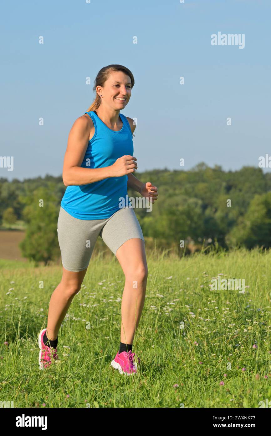 Junge Frau auf einer Wiese laufen Stockfoto