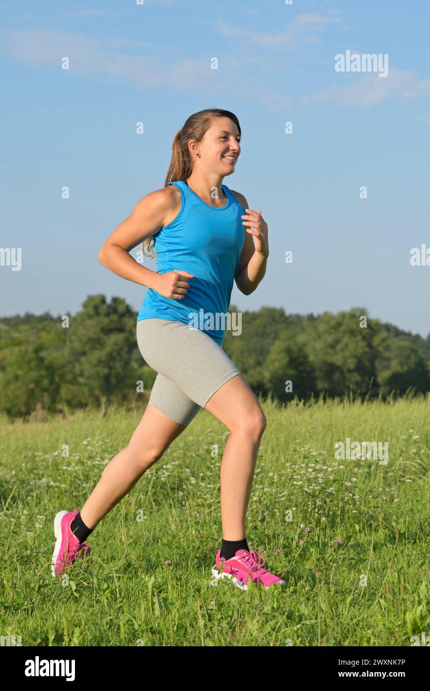 Junge Frau auf einer Wiese laufen Stockfoto