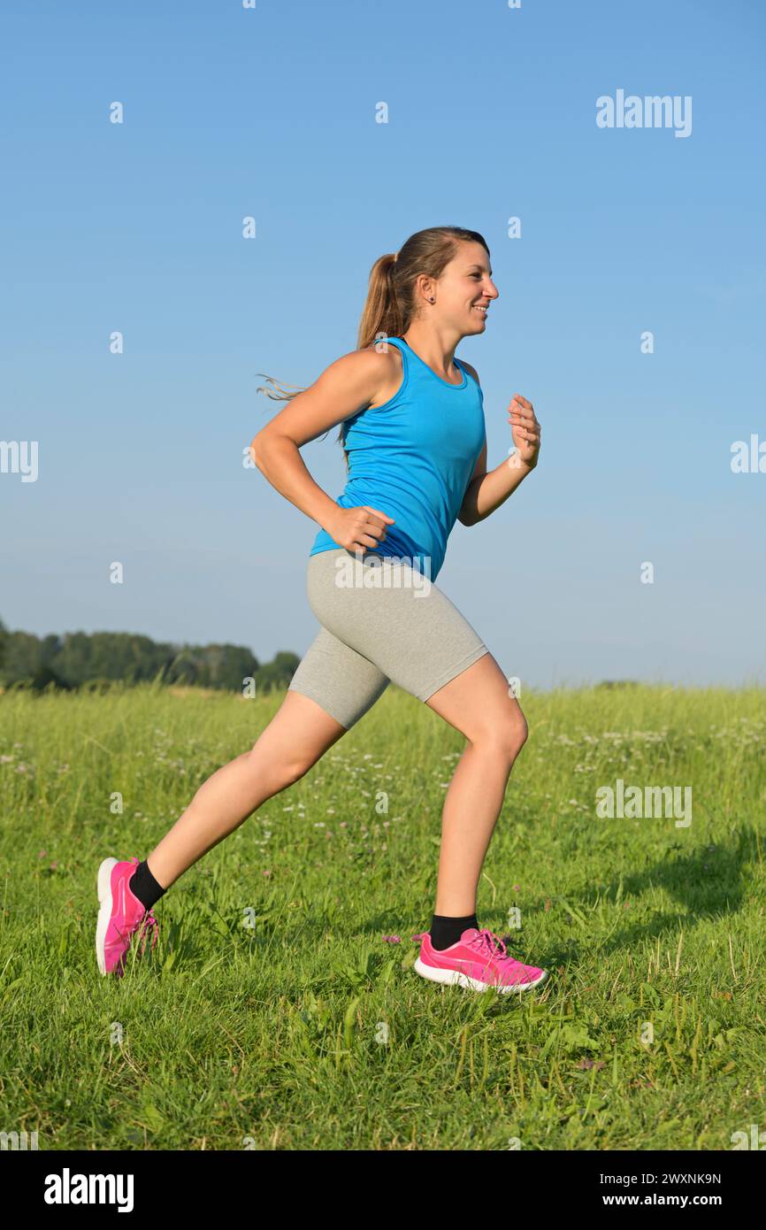 Junge Frau auf einer Wiese laufen Stockfoto