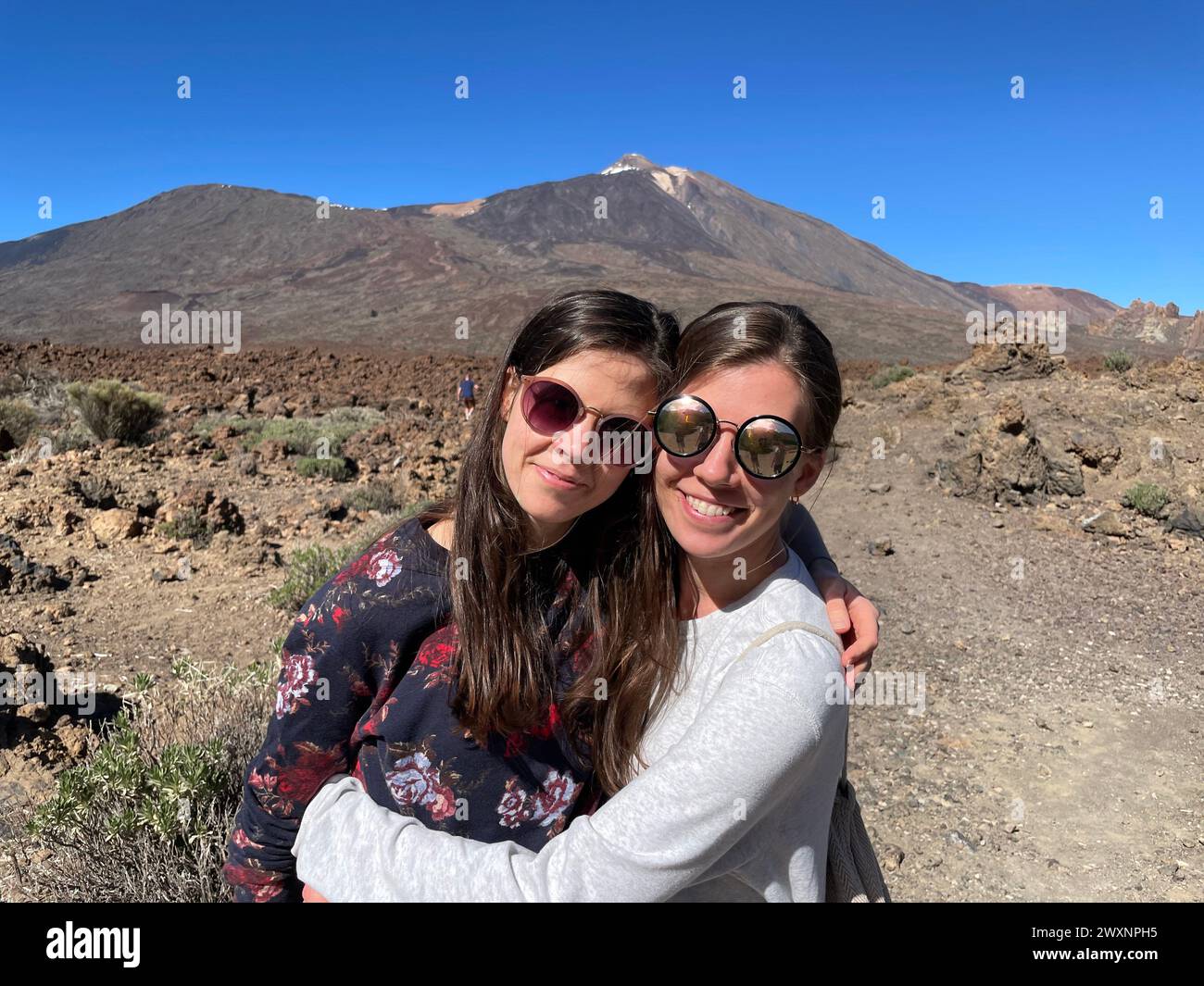 Zwei Frauen umarmen sich in der Wüste mit Bergen im Hintergrund Stockfoto