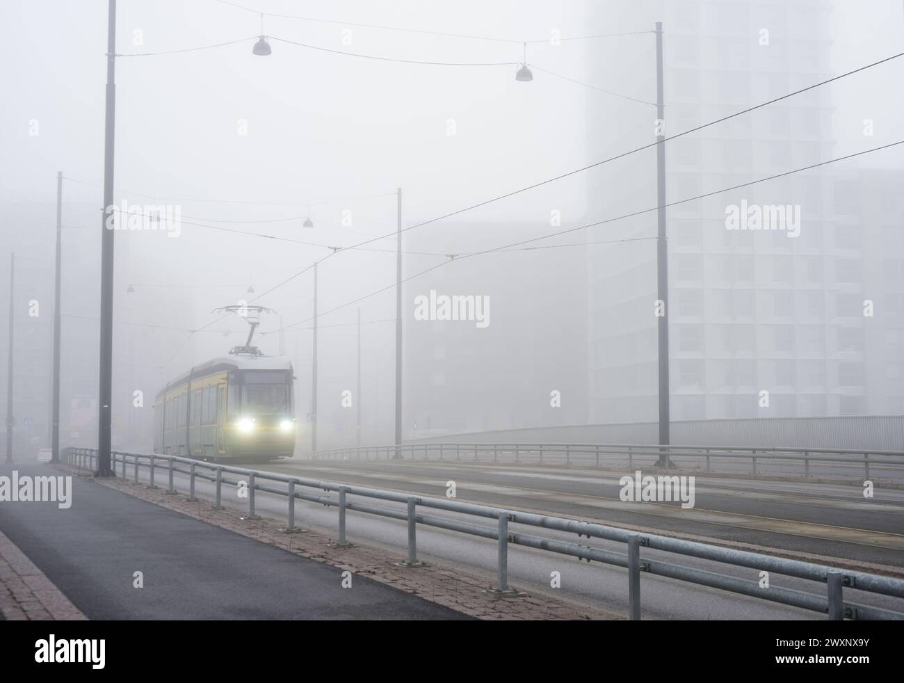 Eine Stadtbahn fährt früh am Morgen bei starkem Nebel durch die Stadt Stockfoto