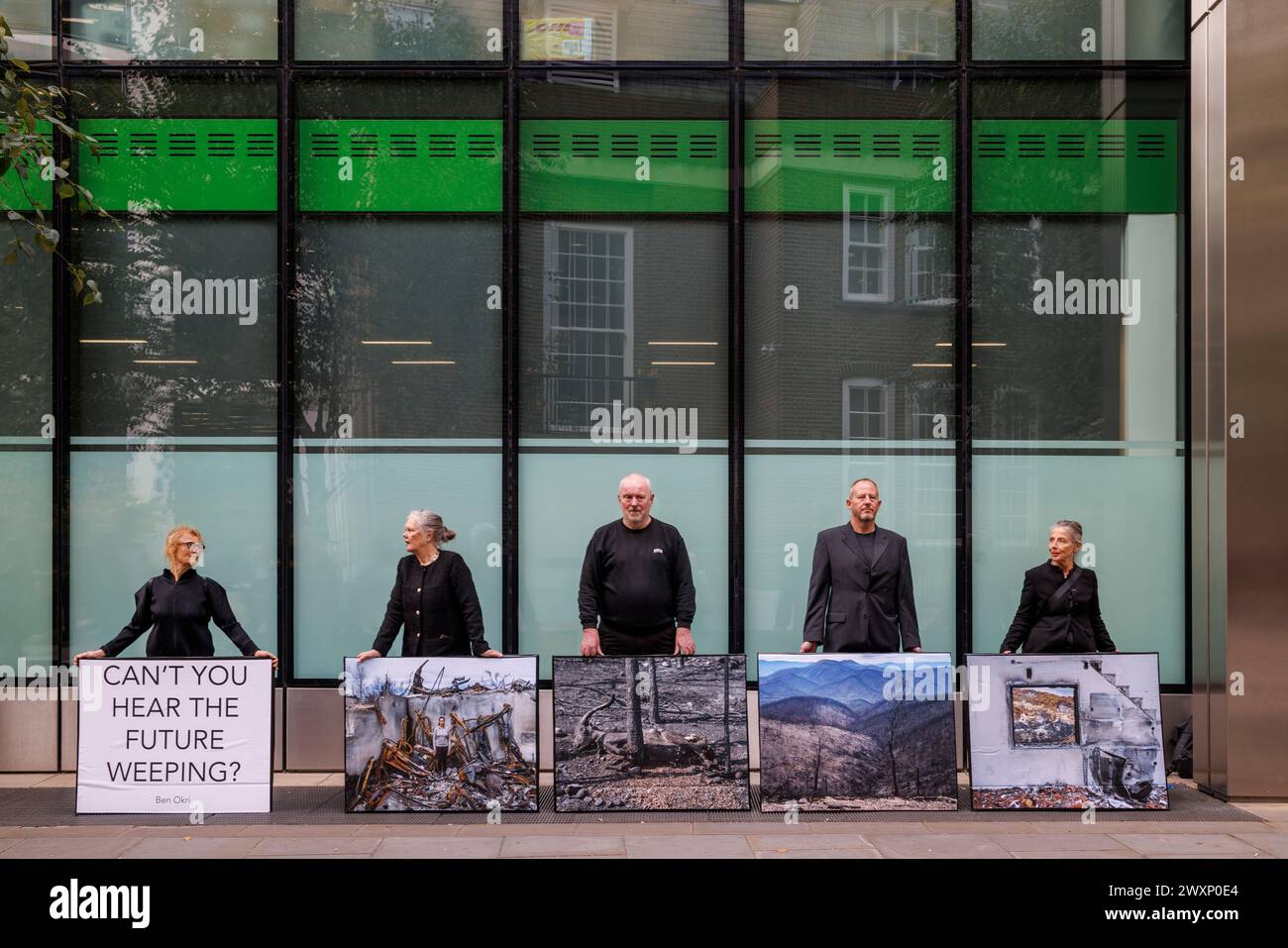 Oktober 2023. Standard Chartered Bank Offices, City of London, UK. Demonstranten der Money Rebellion zeigen eine Ausstellung mit Fotos von Gideon Mendel. Die Pop-up-Ausstellung ist ein Widerspruch zur Standard Chartered Bank, die erneut den Wettbewerb „Wetterfotograf des Jahres“ sponsert. Diese Greenwashing-Übung fängt das dramatische Spektakel extremer Wetterereignisse weltweit ein, lässt aber die Rolle der Bank bei ihrer Entwicklung völlig außer Acht. Oft werden diese fesselnden Schnappschüsse auch nicht in größeren Ruinenszenen kontextualisiert, was darauf hindeutet, dass extremes Wetter schön ist, subli Stockfoto