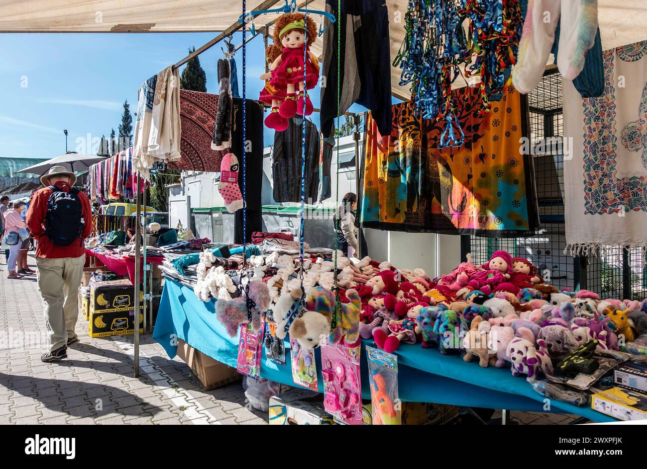 Ein Markt im Freien bietet eine Vielzahl von Artikeln zum Verkauf, darunter bunte Kuscheltiere, Puppen und Kleidung in Quarteira, Portugal. Stockfoto