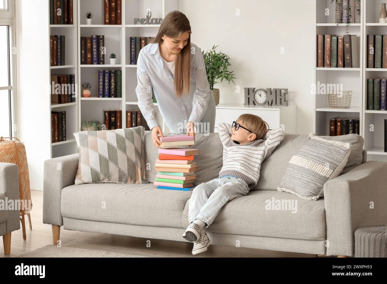 Süßer kleiner Junge und seine Mutter mit verschiedenen Büchern zu Hause Stockfoto