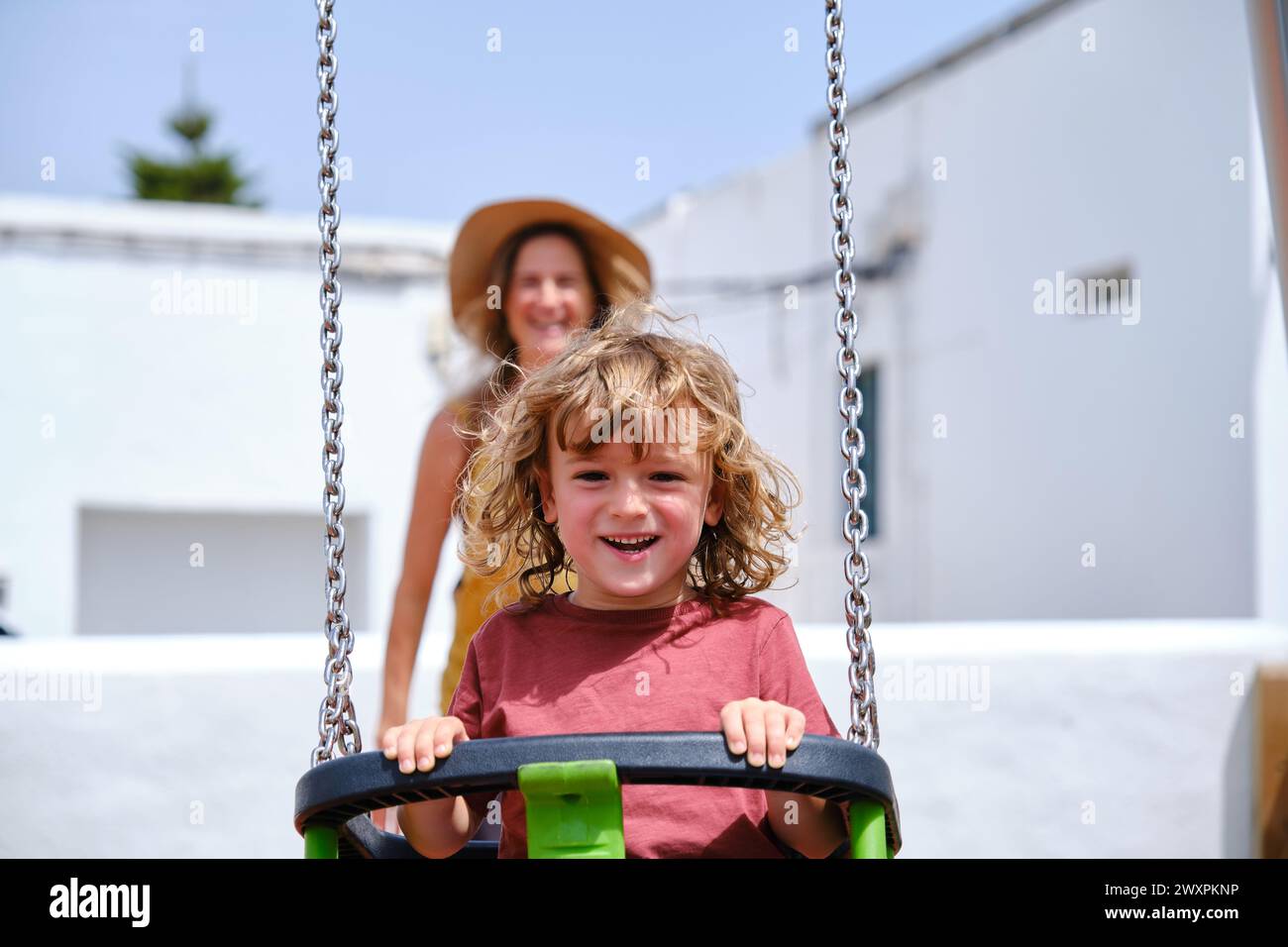 Kind, das Spaß mit seiner Mutter auf der Schaukel hat Stockfoto