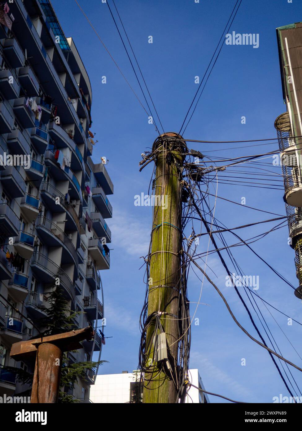 Viele Drähte sind auf einem Holzmast in einer modernen Stadt gestapelt. Elektrifizierung einer asiatischen Stadt. Vintage-Technologie. Unbequeme Infrastruktur Stockfoto