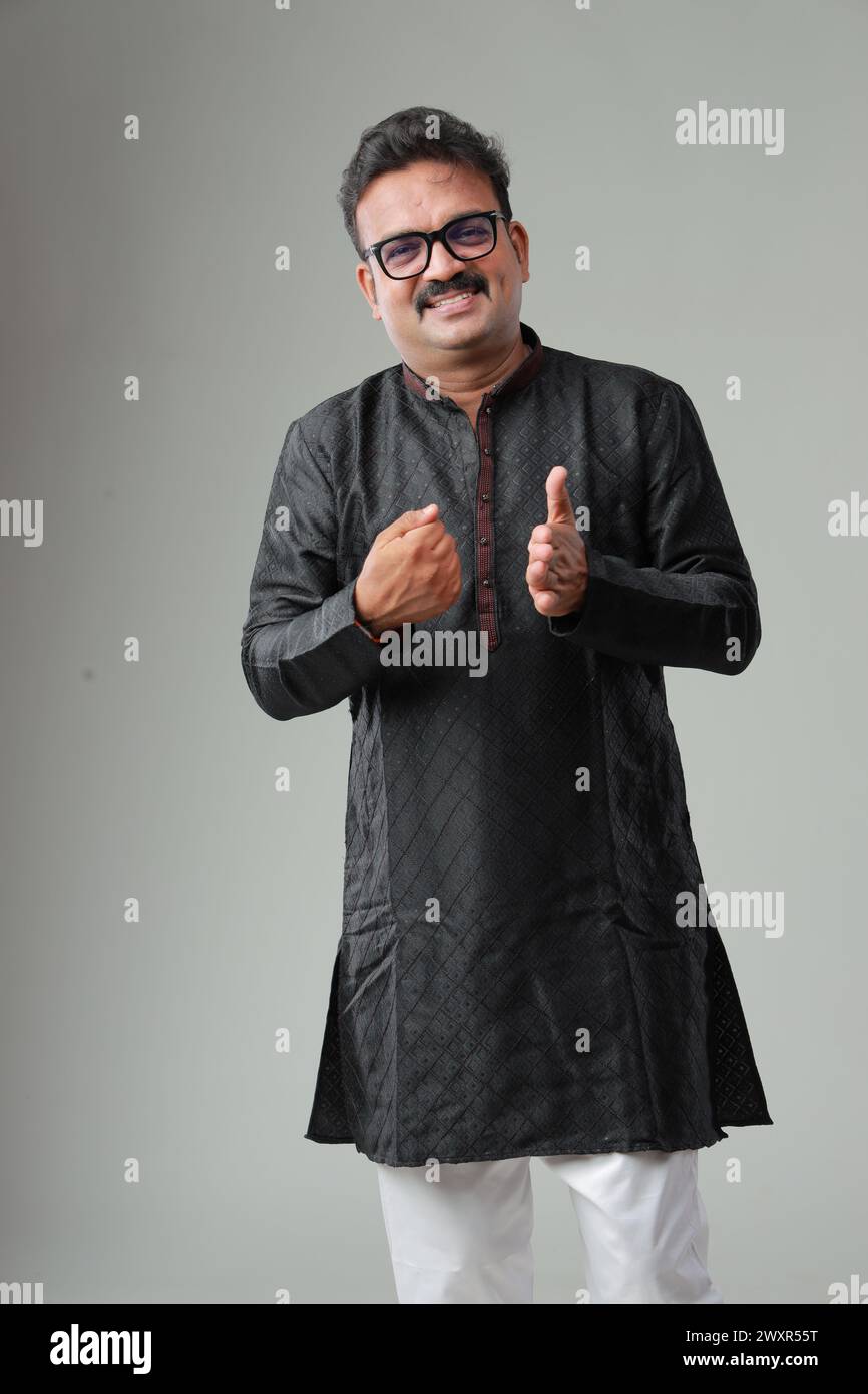 Ein Mann mit traditioneller indischer Tracht, mit schlichtem Hintergrund, isoliert, mit schwarzer Kurta und weißem Pyjama. Stockfoto