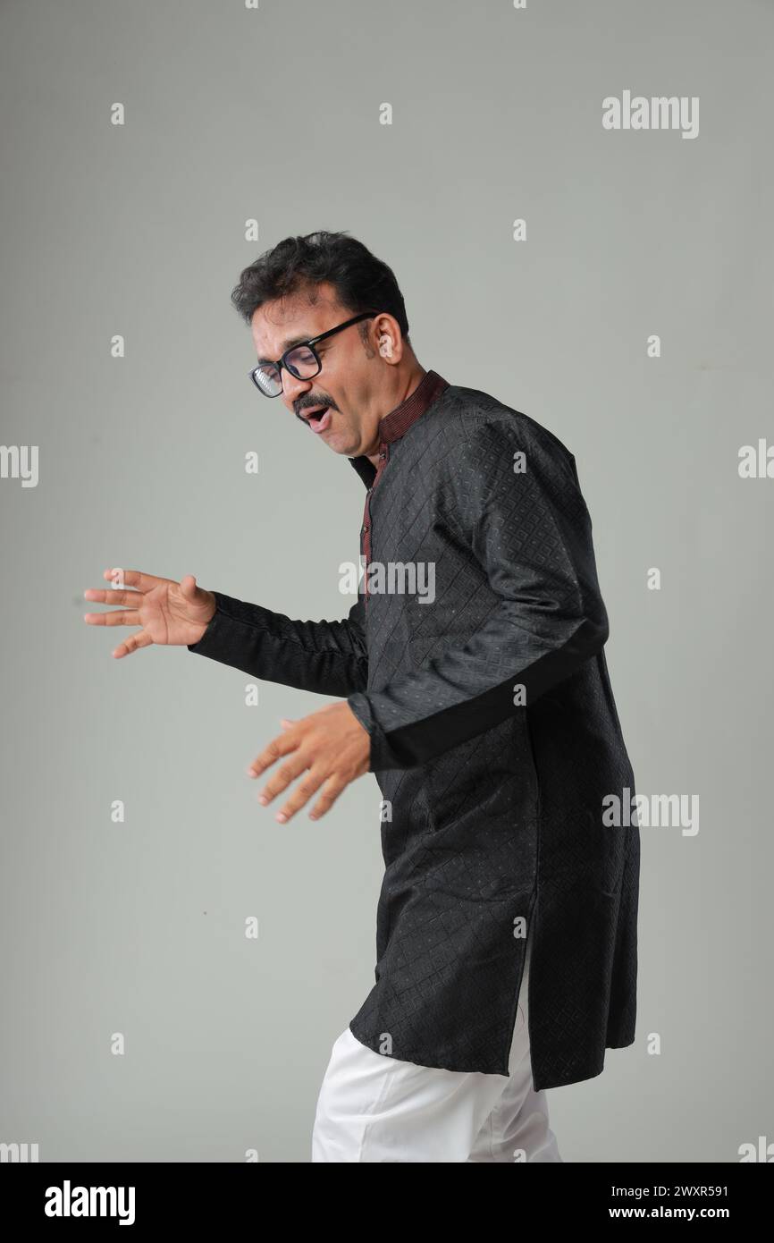 Ein Mann mit traditioneller indischer Tracht, mit schlichtem Hintergrund, isoliert, mit schwarzer Kurta und weißem Pyjama. Stockfoto