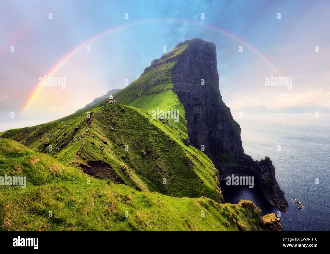Färöer in Dänemark mit Regenbogen - Leuchtturm Kallur auf grünen Hügeln der Insel Kalsoy bei Sonnenuntergang, Landschaftsfotografie Stockfoto