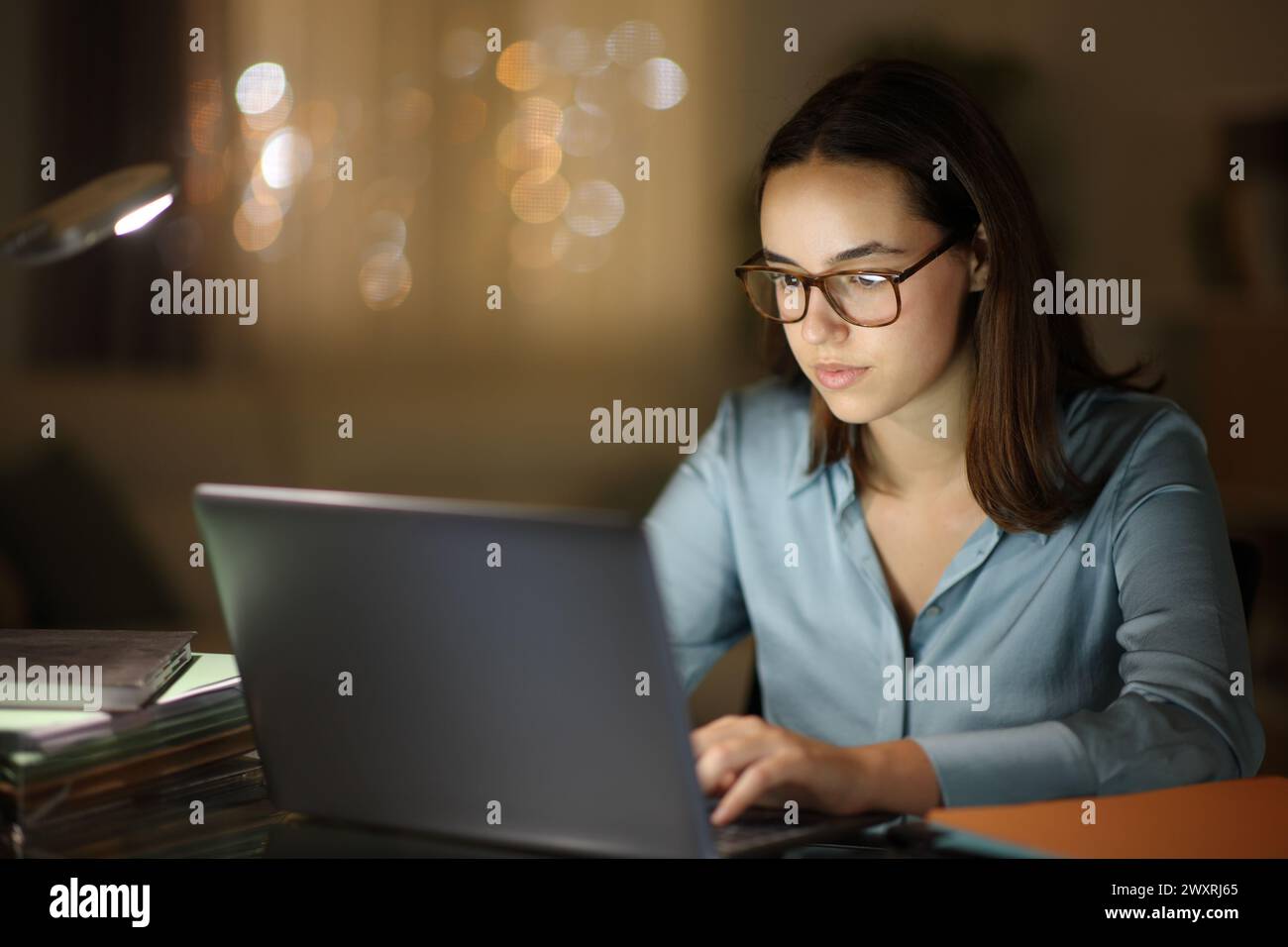 Tele-Mitarbeiter, der nachts im Home Office mit einer Brille arbeitet, mit einem Laptop Stockfoto