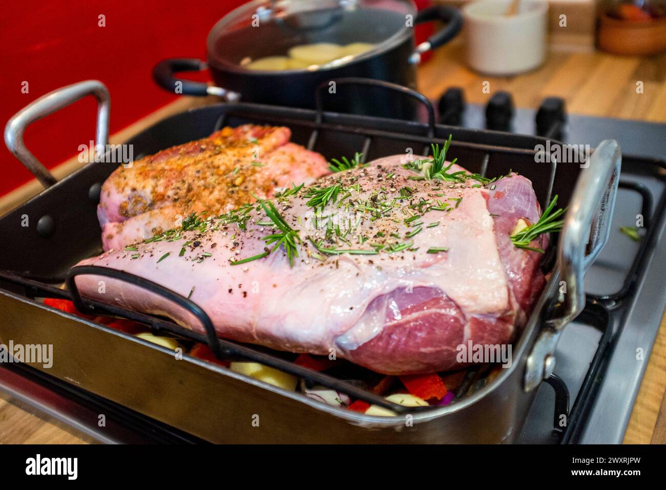 Zubereitung einer Schenkel und einer kleinen Lammschulter zum Rösten mit Knoblauch- und Rosmarinkräutern Stockfoto