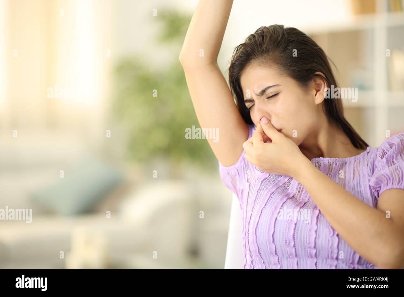 Frau beschwert sich über schlechten Geruch im Achselbereich zu Hause Stockfoto