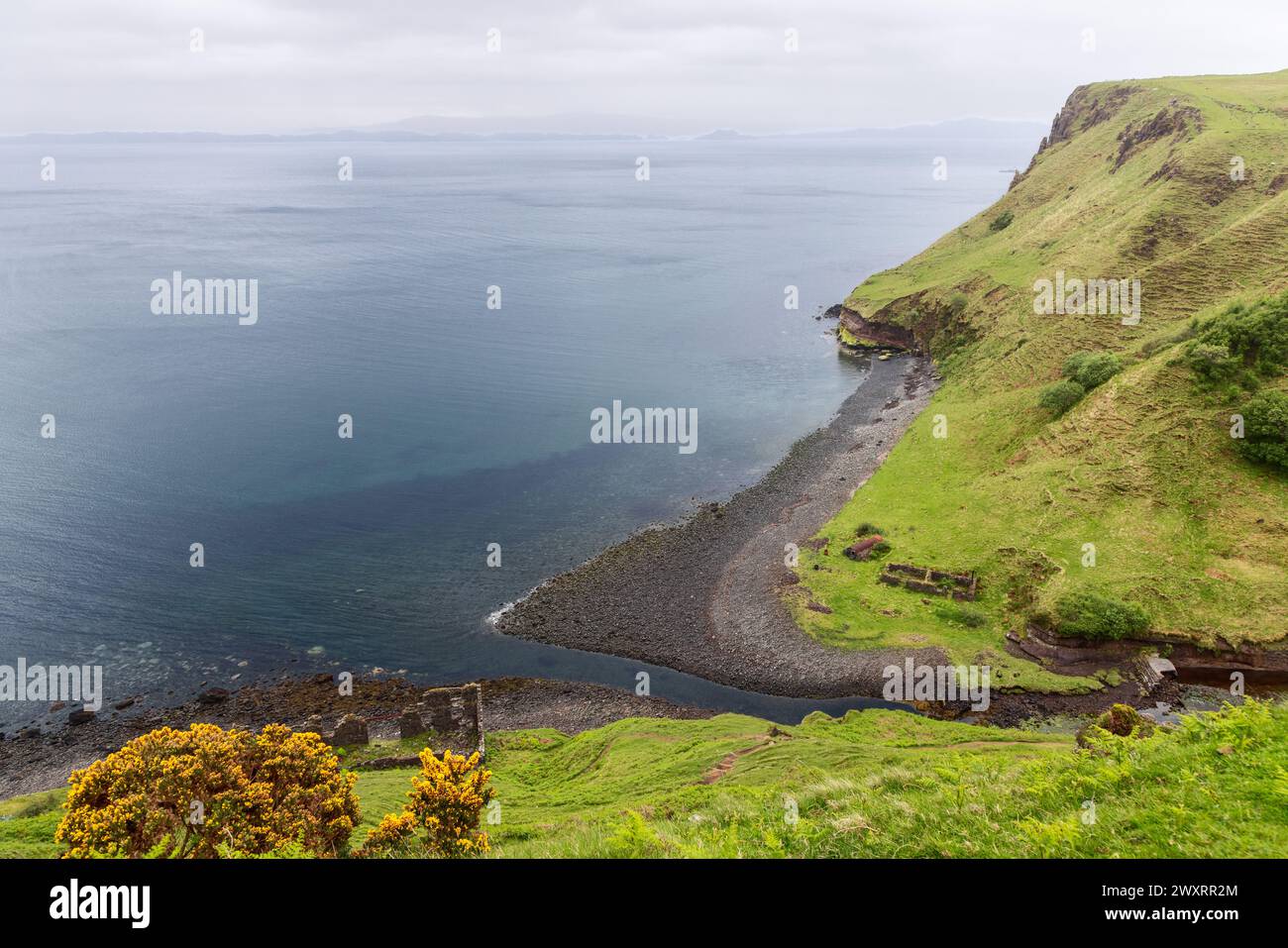 Die Küste in der Nähe der Lealt Falls auf der Isle of Skye ist mit einem Kiesstrand und grasbewachsenen Klippen geschmückt Stockfoto