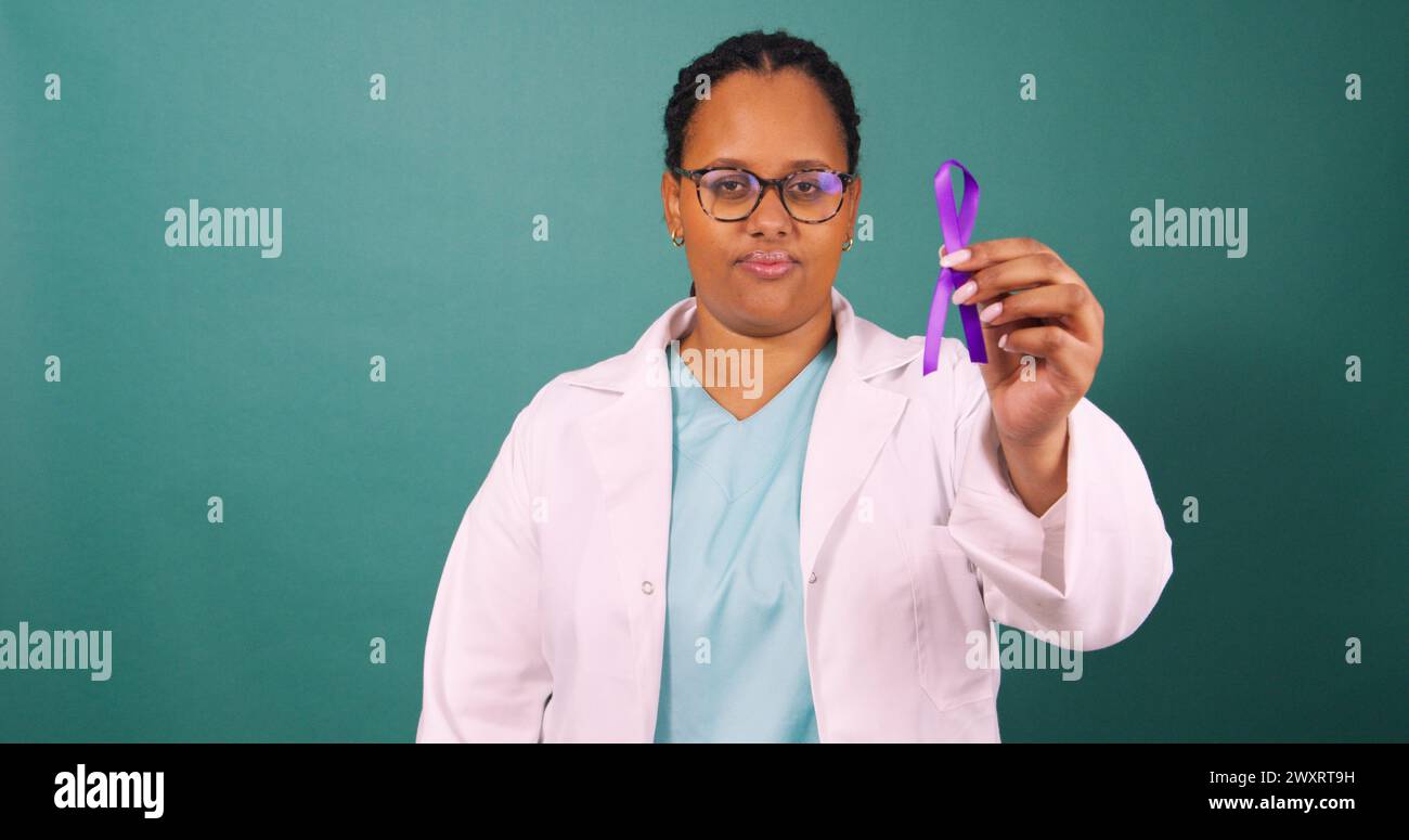 Schwarze Ärztin, die ein violettes Wahrnehmungsband hält, ernst mit weißem Fell Stockfoto