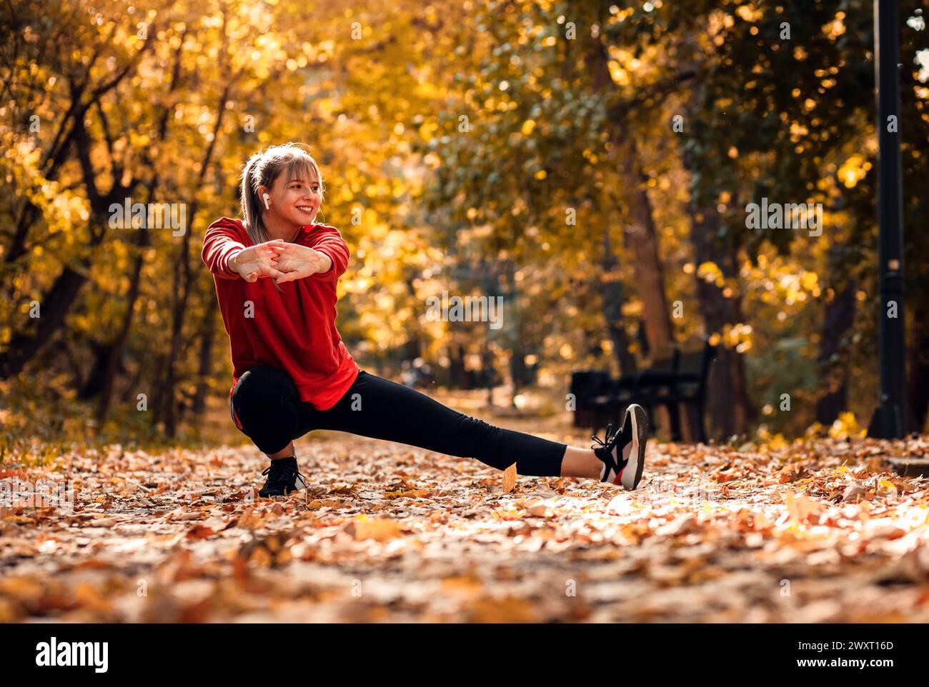 Junge Frau, die sich aufwärmt und sich dehnt, bevor sie im Park läuft. Stockfoto