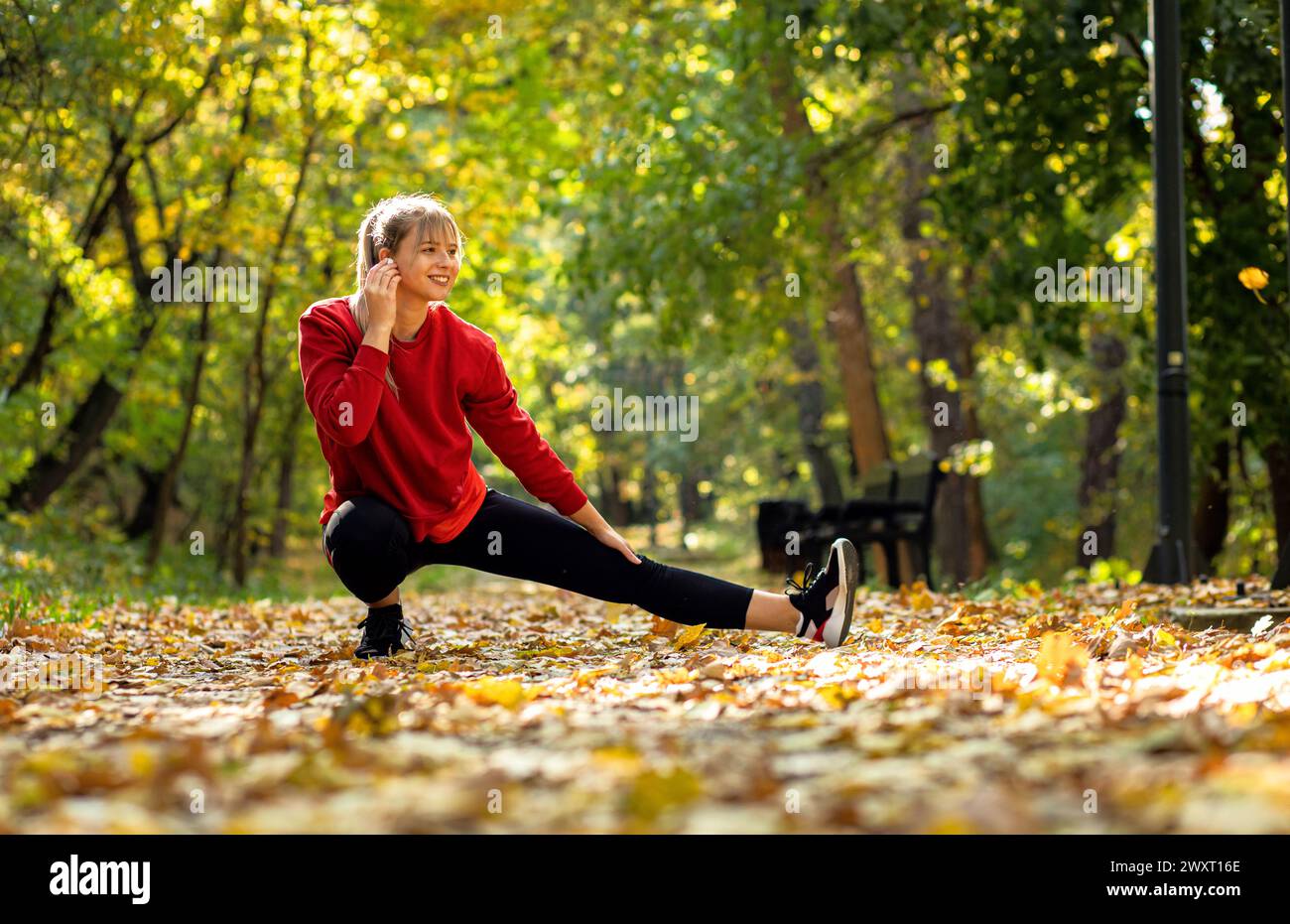 Junge Frau, die sich aufwärmt und sich dehnt, bevor sie im Park läuft. Stockfoto