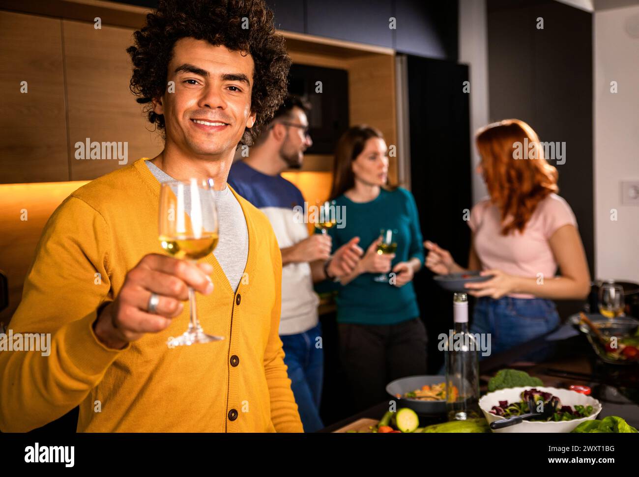 Porträt eines Mannes mit einem Glas Wein, der zu Hause mit Freunden eine Party feiert. Stockfoto