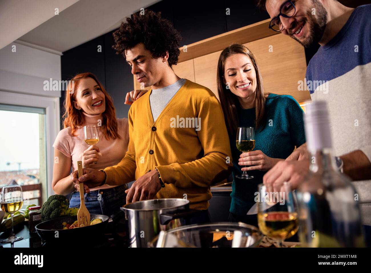 Gruppe von Freunden, die zu Hause eine Dinnerparty feiern, Wein trinken und vegetarisches Essen essen. Stockfoto