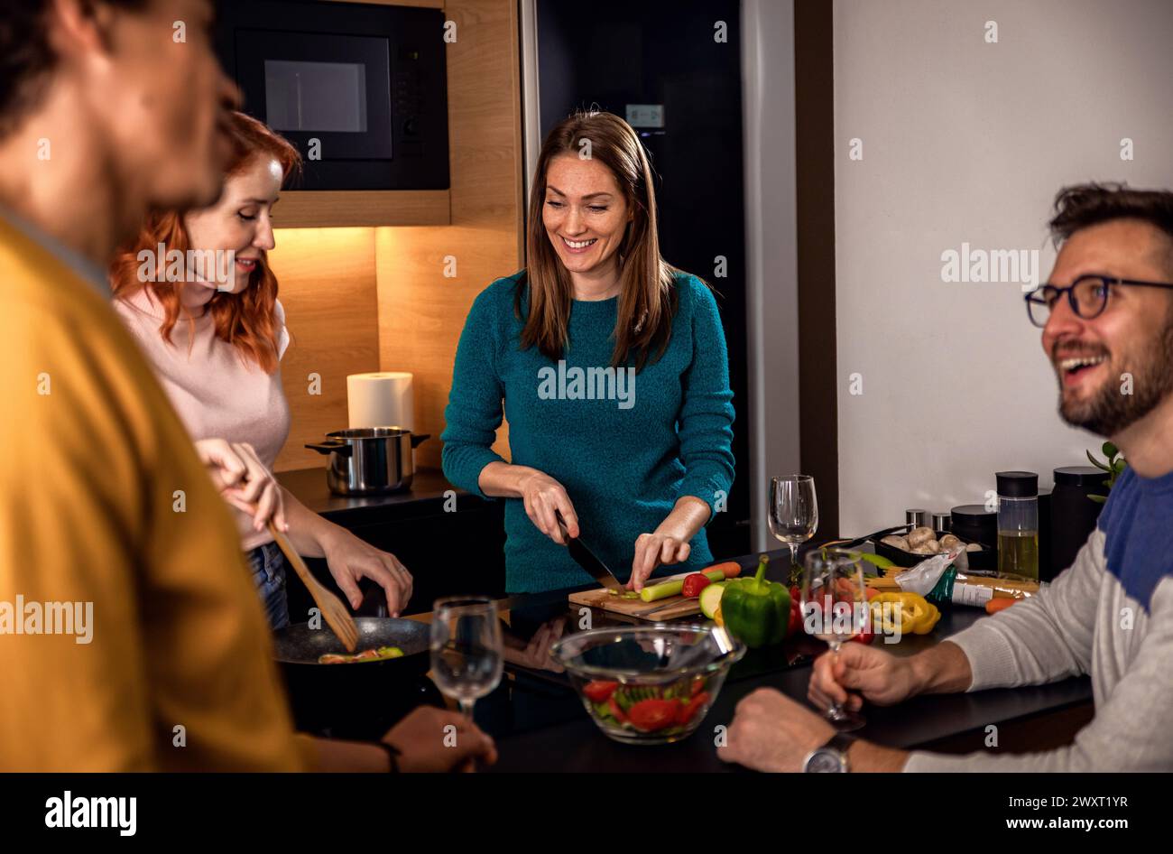 Gruppe von Freunden, die zu Hause eine Dinnerparty feiern, Wein trinken und vegetarisches Essen essen. Stockfoto