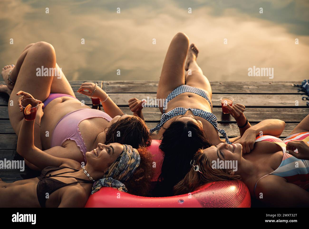 Eine Gruppe weiblicher Freunde genießt einen Sommertag am Pier am See. Stockfoto
