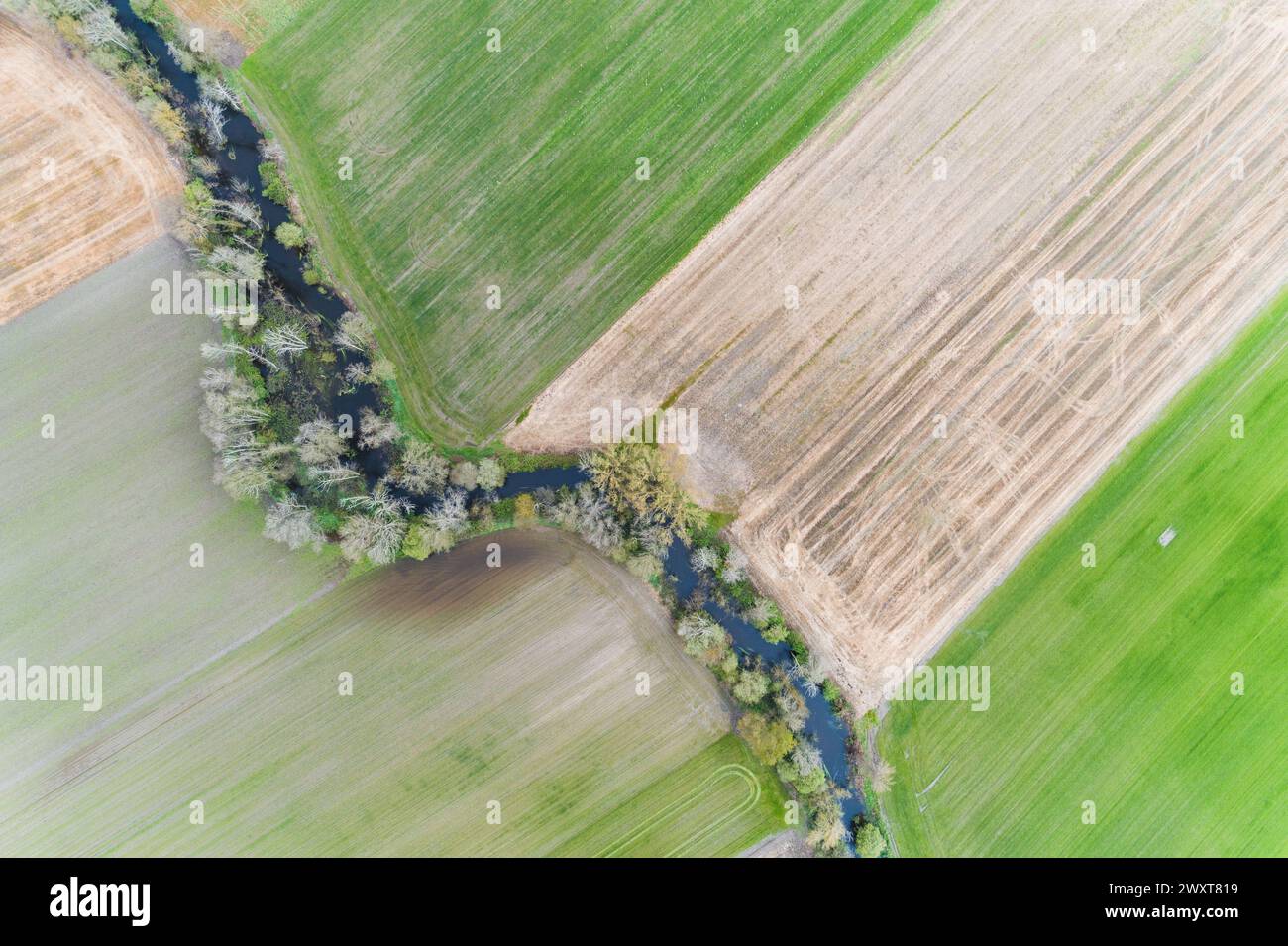Ein Fluss zwischen landwirtschaftlichen Feldern, von einer Drohne aus gesehen Stockfoto