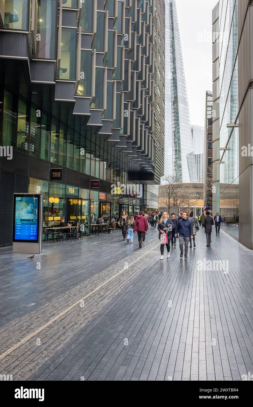 Menschen, die kleine Unternehmen zwischen modernen Gebäuden vorbeifahren, mit dem legendären Shard-Wolkenkratzer im Hintergrund Stockfoto