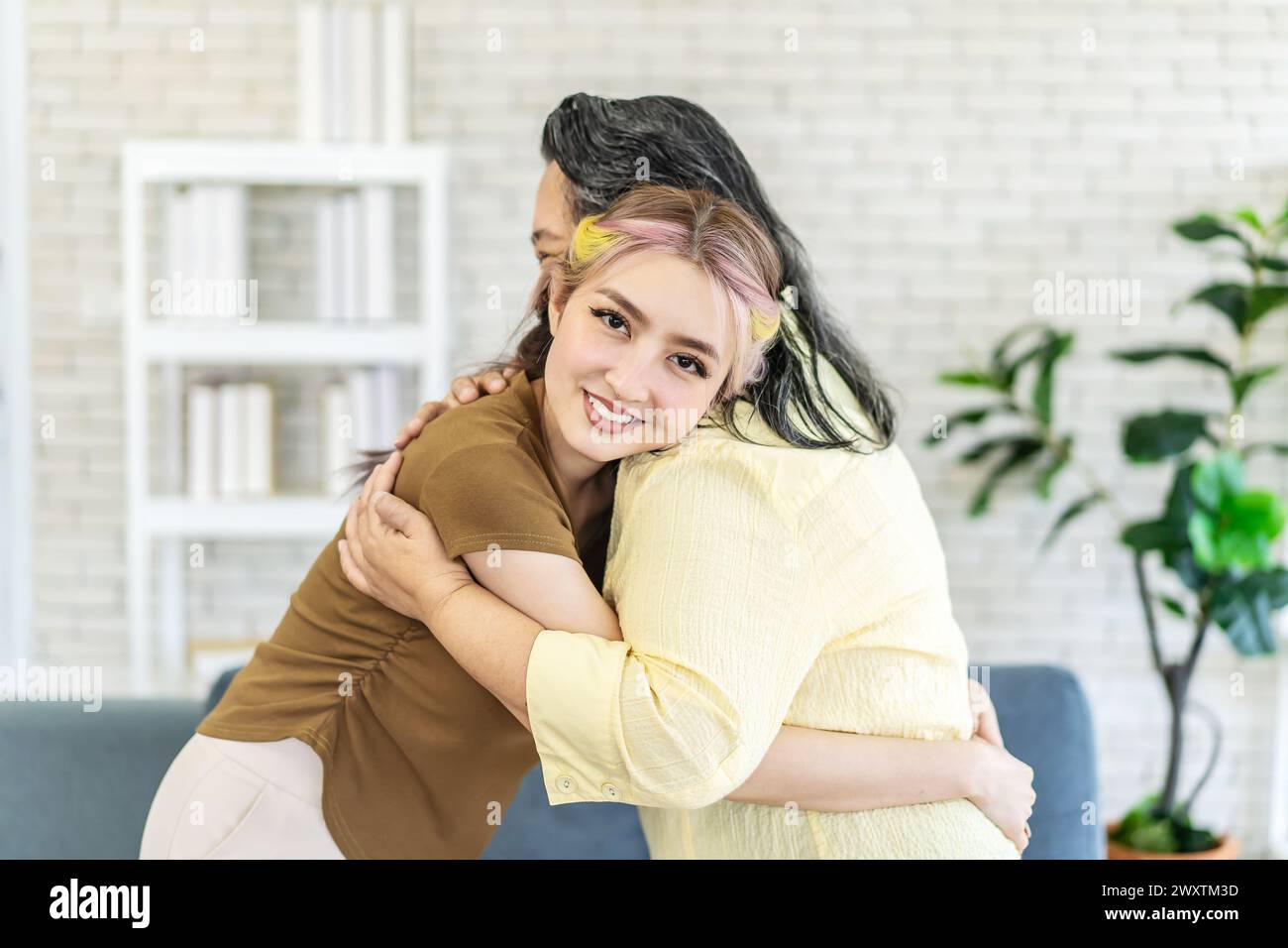 Die schöne Tochter umarmt ihre Mutter auf dem unscharfen Hintergrund Stockfoto