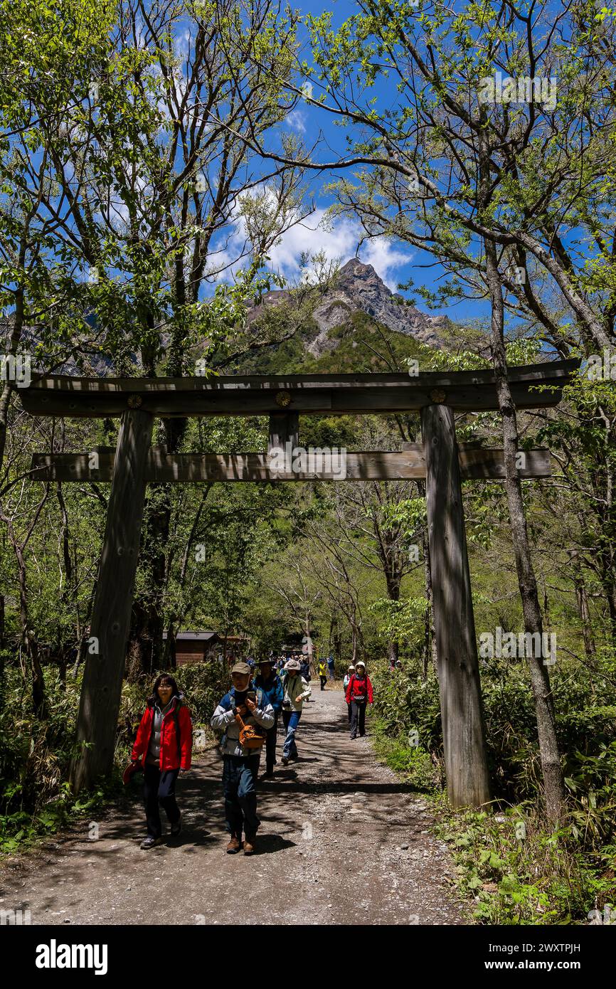 KAMIKOCHI, JAPAN - 24. MAI 2023: Wanderer, die unter dem Torii-Tor des Hotaka-Schreins in Kamikochi, Nagano, Japan passieren. Stockfoto