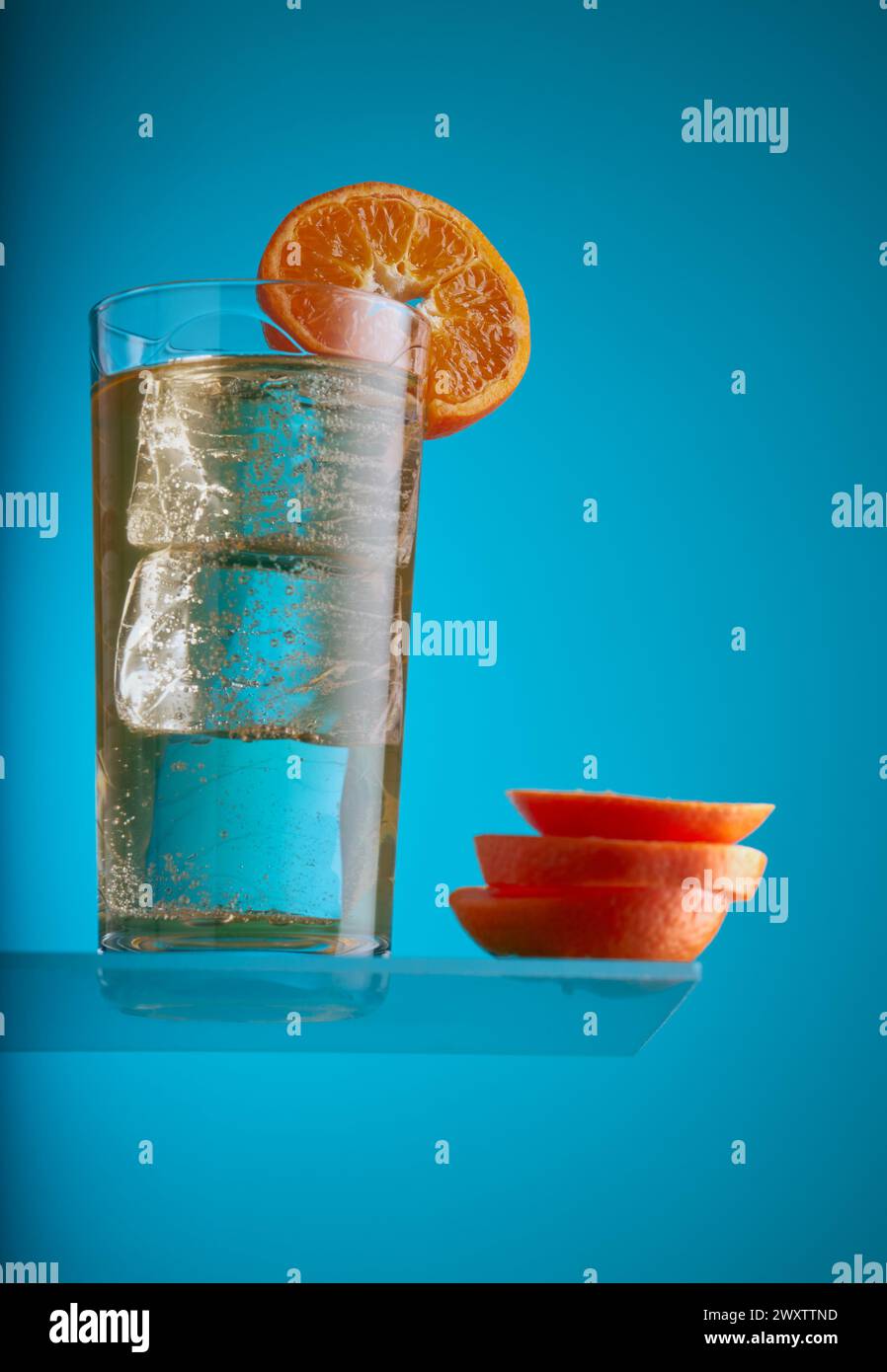 Cocktail-Getränk mit Eis und garniert mit einer Scheibe Orange auf blauem Hintergrund. Stockfoto