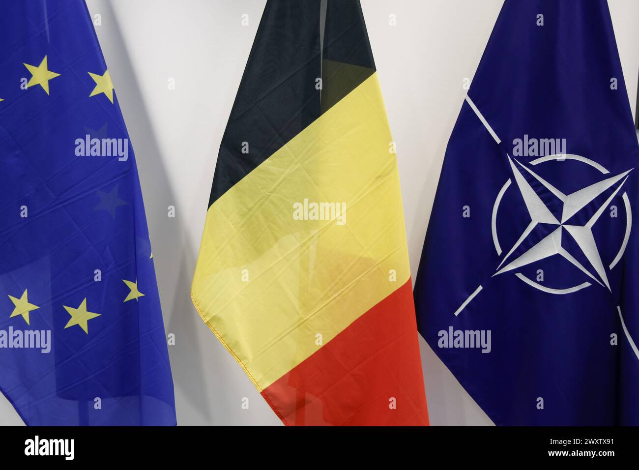 Brüssel, Belgien April 2024. Die europäische, belgische und NATO-Flagge, die bei der offiziellen Präsentation der neuen Euro-Gedenkmünze anlässlich des 75-jährigen Jubiläums der NATO-Militärallianz (Nordatlantikvertragsorganisation) am Dienstag, den 2. April 2024 in Brüssel abgebildet ist. BELGA FOTO NICOLAS MAETERLINCK Credit: Belga News Agency/Alamy Live News Stockfoto