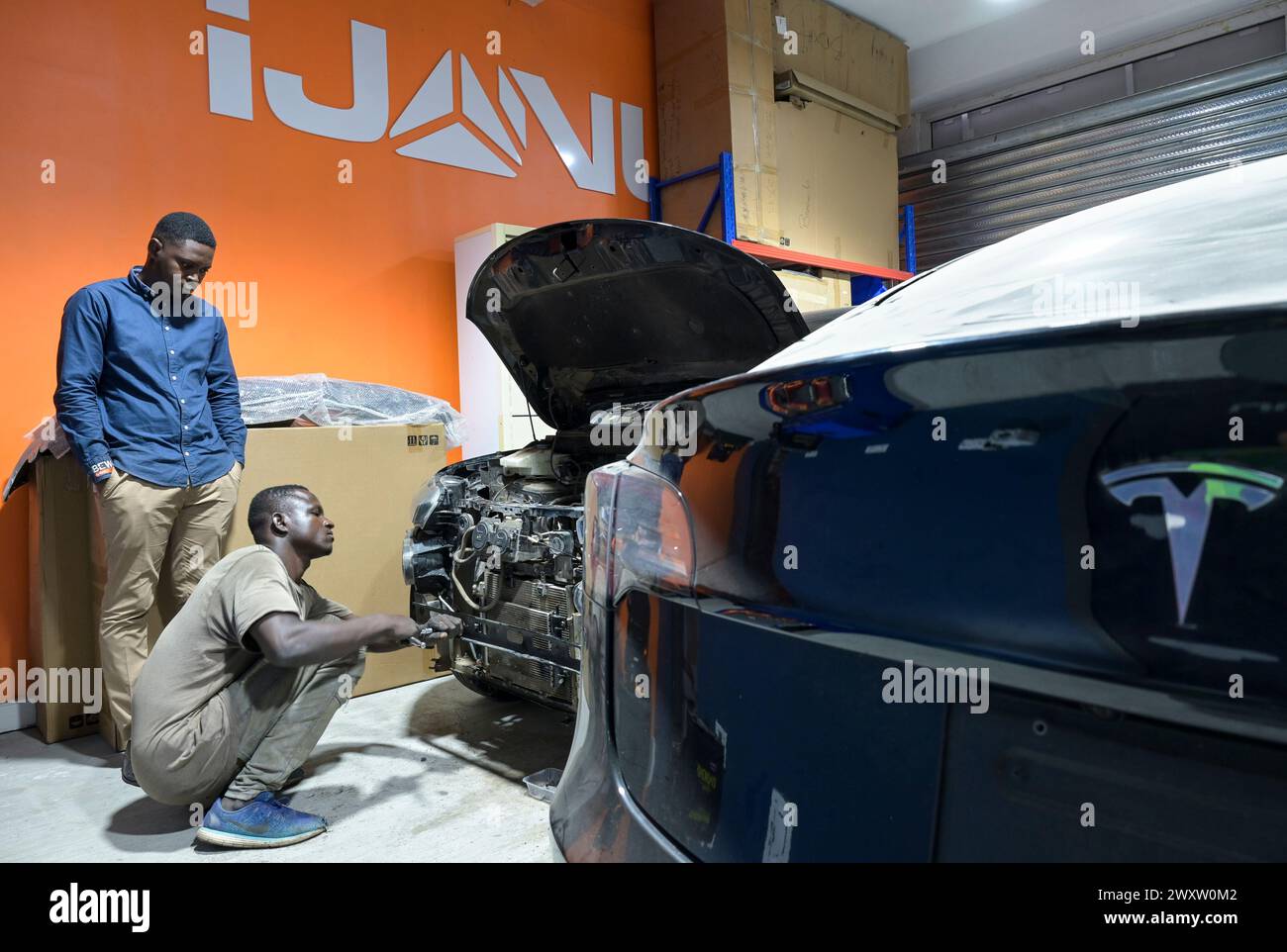 GHANA, Accra, Elektromobilität, IJANU Service und Schnellladestation für Elektroautos, Reparatur von E-cras / GHANA, Accra, E-Mobilität, IJANU Service und Ladestation für E-Autos, Vordergrund Tesla Auto Stockfoto