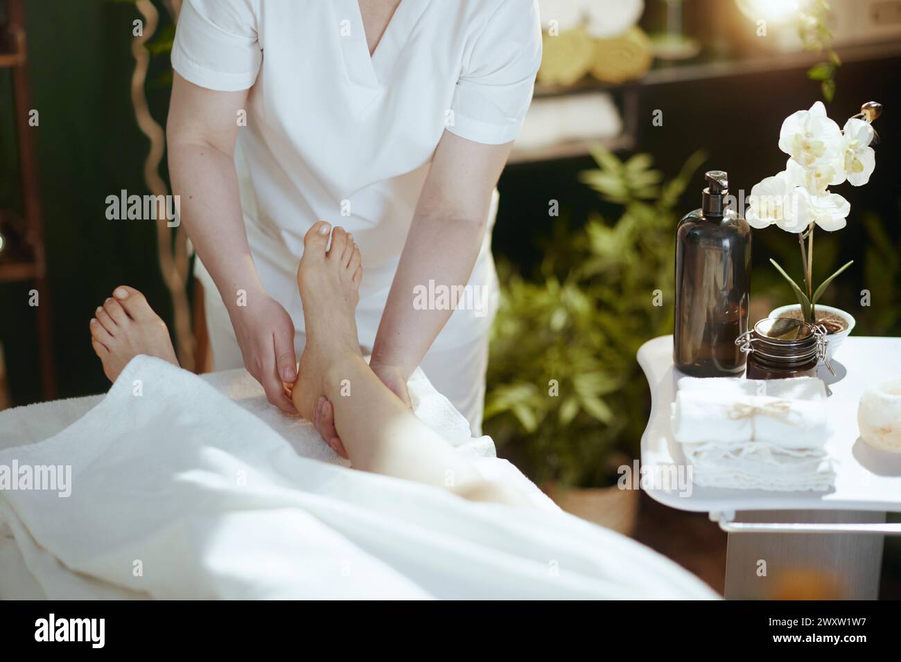 Gesundheitszeit. Nahaufnahme eines Massagetherapeuten im Spa-Salon, der den Fuß auf dem Massagetisch massiert. Stockfoto