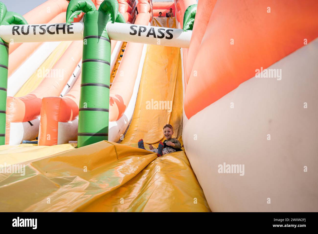 Bad Gleichenberg, Österreich - 30. März 2024 - Ein Junge auf einer aufblasbaren Rutsche im Freien Stockfoto