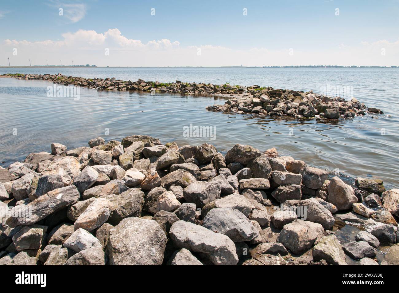 Große Felsbrocken, die Wellenbrecher im Grevelinger See bilden, um den kleinen Strand nahe Battenoord bei Goeree-Overflakkee in den Niederlanden vor schützen zu können Stockfoto