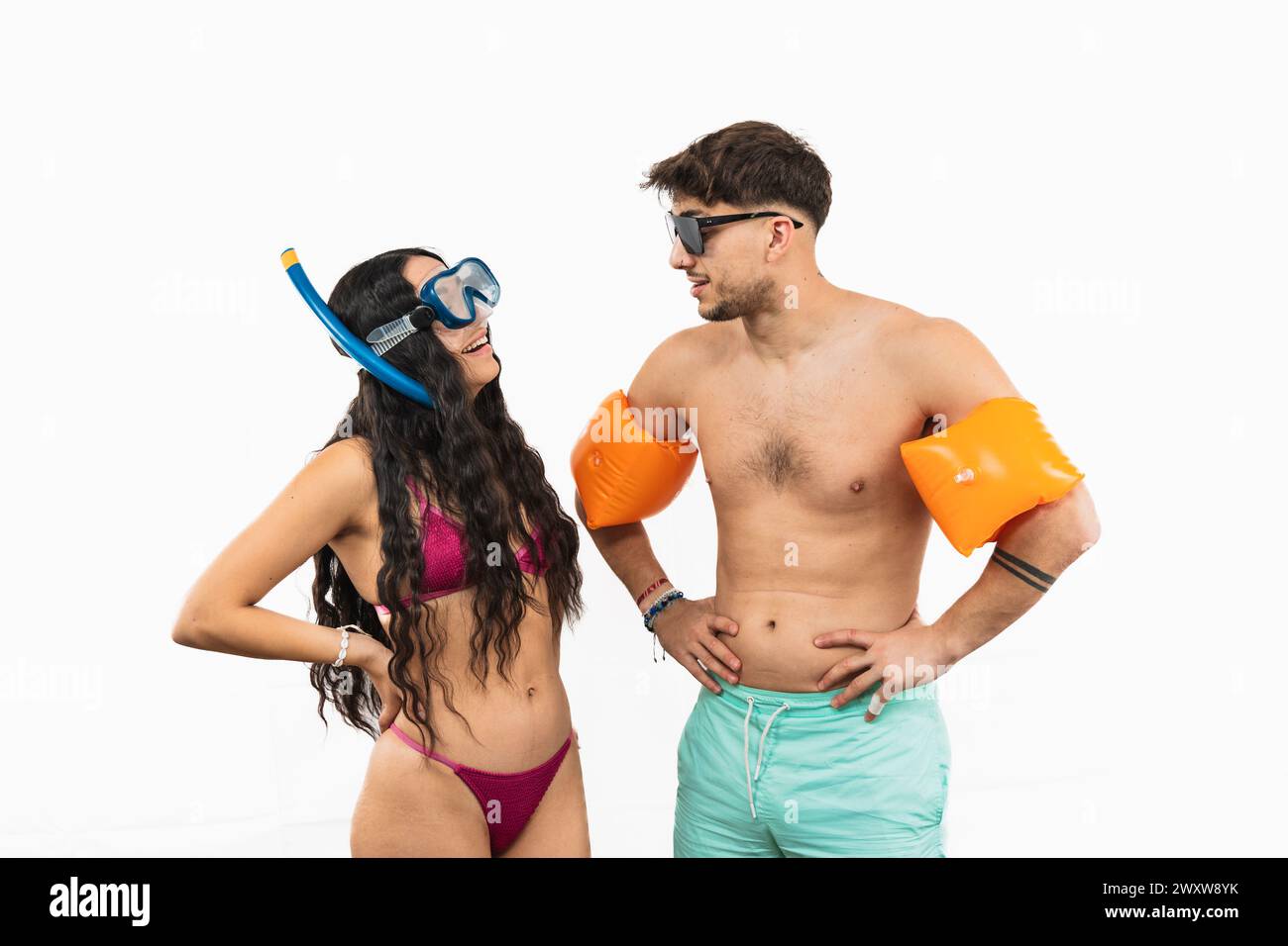 Abenteuerlustiges multikulturelles Paar ist auf einen Tag am Strand vorbereitet. Die Latina trägt einen Bikini und Schnorchelausrüstung, während der Mann Badehosen trägt Stockfoto