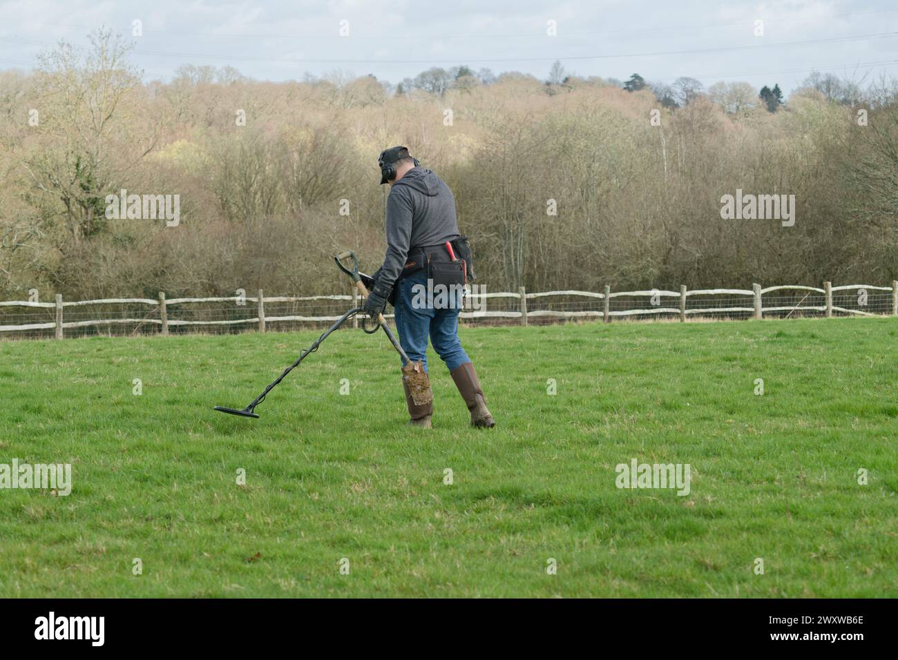 Ein Metalldetektor auf einem Feld, der nach Metallgegenständen sucht, die im Boden versteckt sind. Mann mit Metalldetektor. Stockfoto