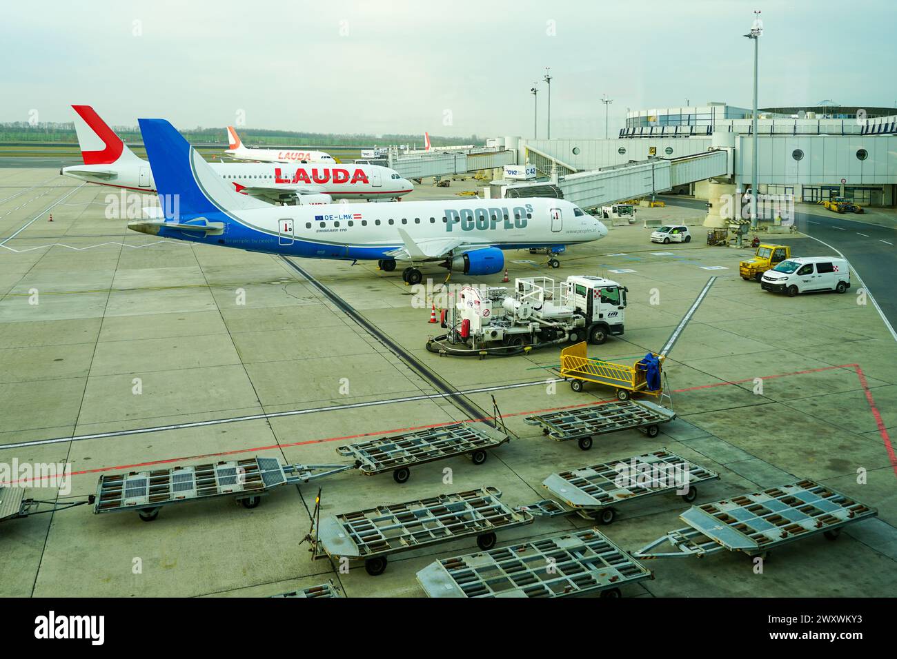 Wien, Österreich- 05. März 2024: People Embraer 170 OE-LMK Passagierflugzeug am internationalen Flughafen in Wien, Lauda Air Flugzeug im Hintergrund Stockfoto