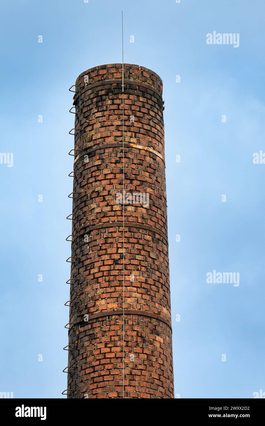 Historischer Fabrikschornstein aus Mauerwerk mit Steigeisen und modernem Blitzleiter Stockfoto