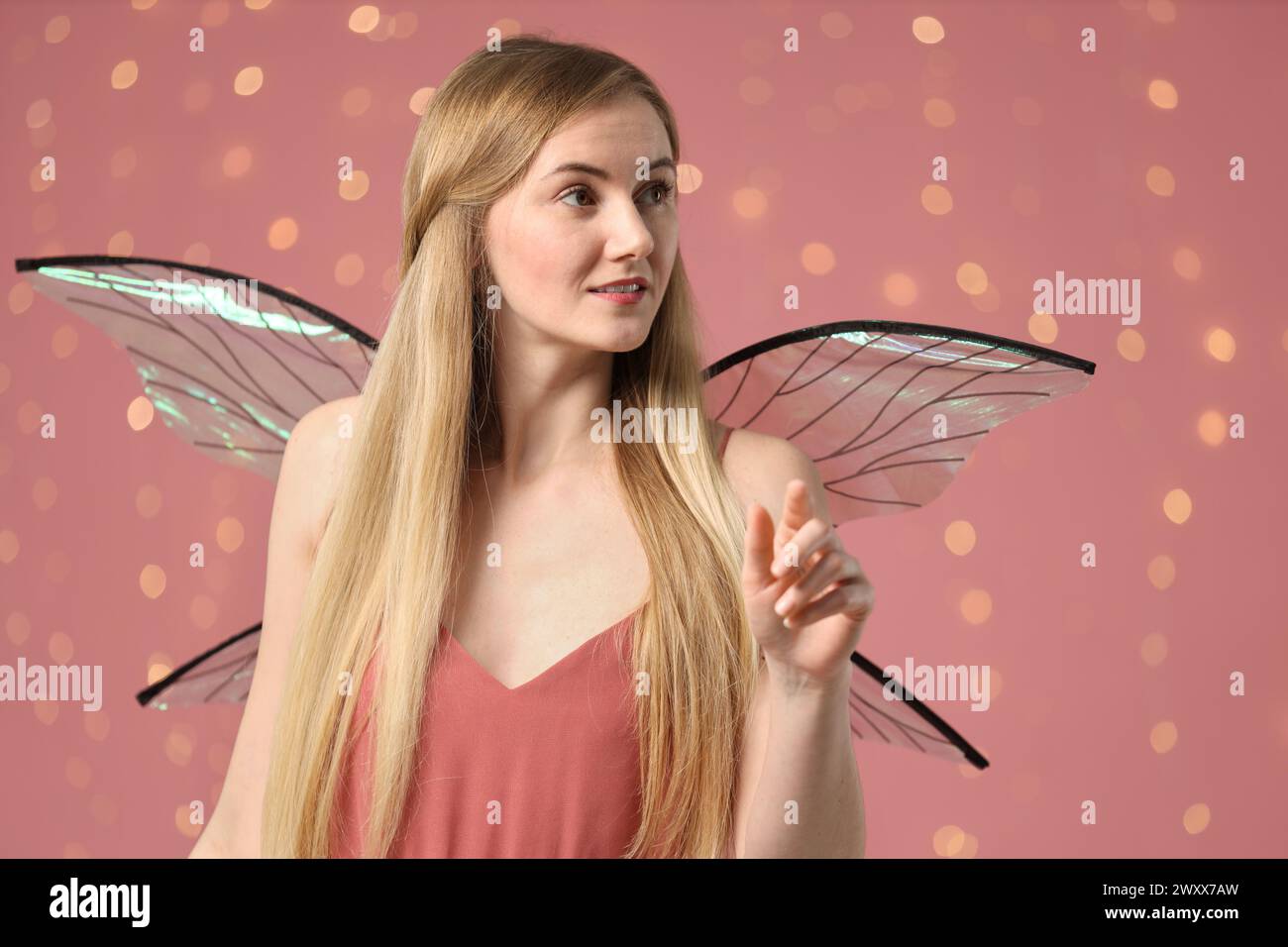 Schönes Mädchen im Feenkostüm mit Flügeln auf rosa Hintergrund Stockfoto