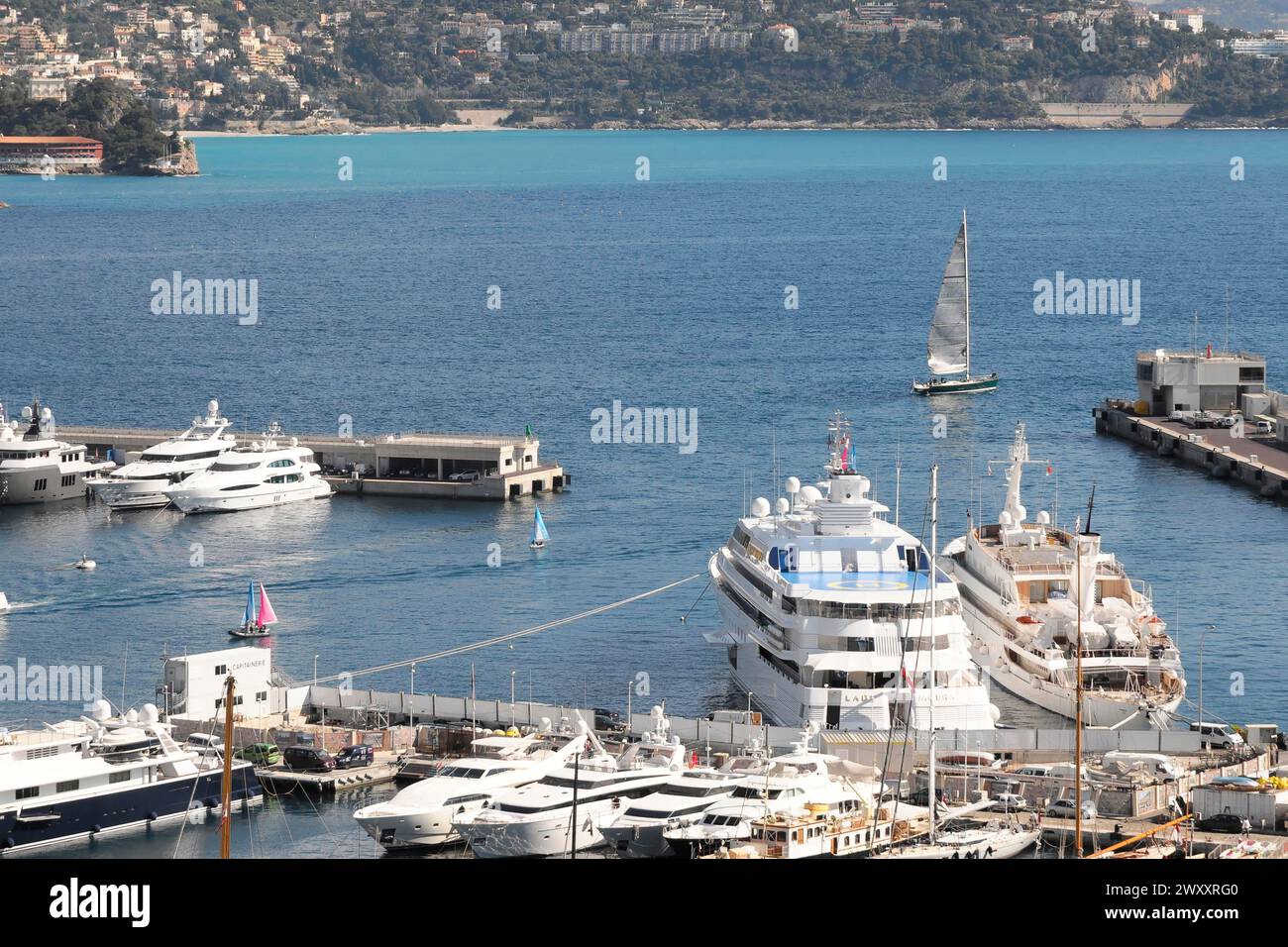 Hafen von Monte Carlo, Yachten und ein Segelboot auf einem klaren blauen Meer in der Nähe der Küste, Monte Carlo, Fürstentum Monaco, Cote d'Azur Stockfoto