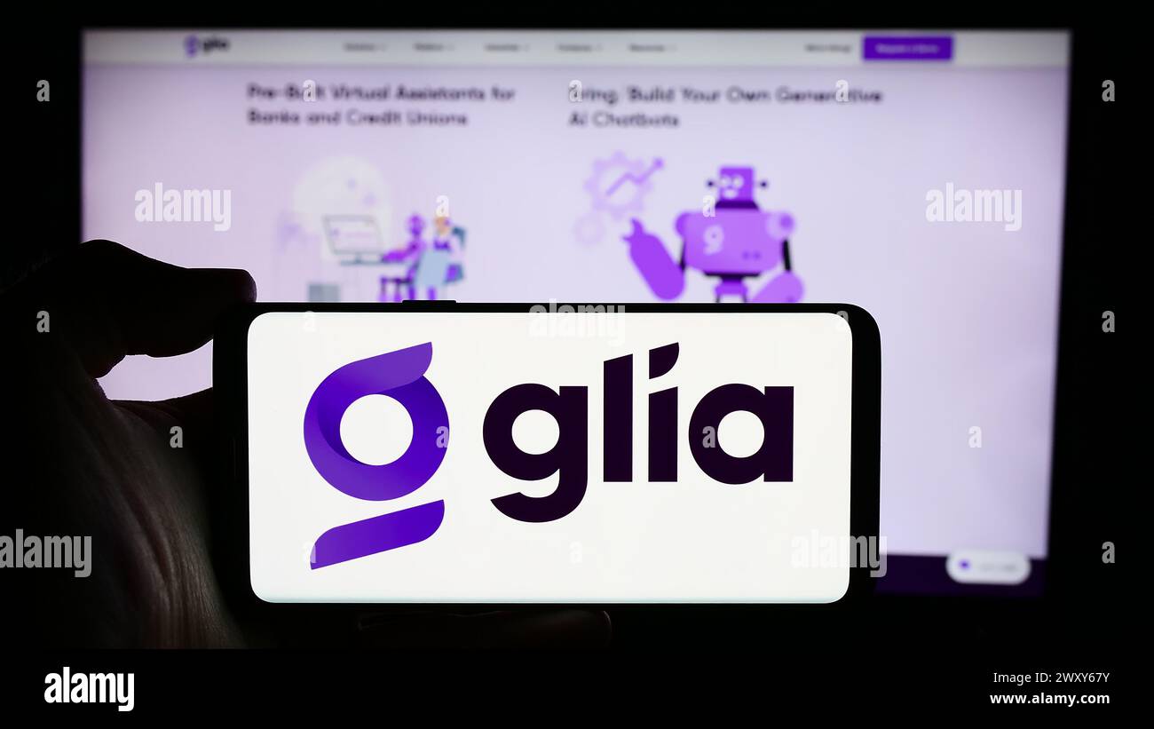 Person, die ein Mobiltelefon mit dem Logo des amerikanischen Unternehmens für Kundeninteraktion Glia Technologies Inc. Vor der Webseite hält. Schwerpunkt auf dem Display des Telefons. Stockfoto