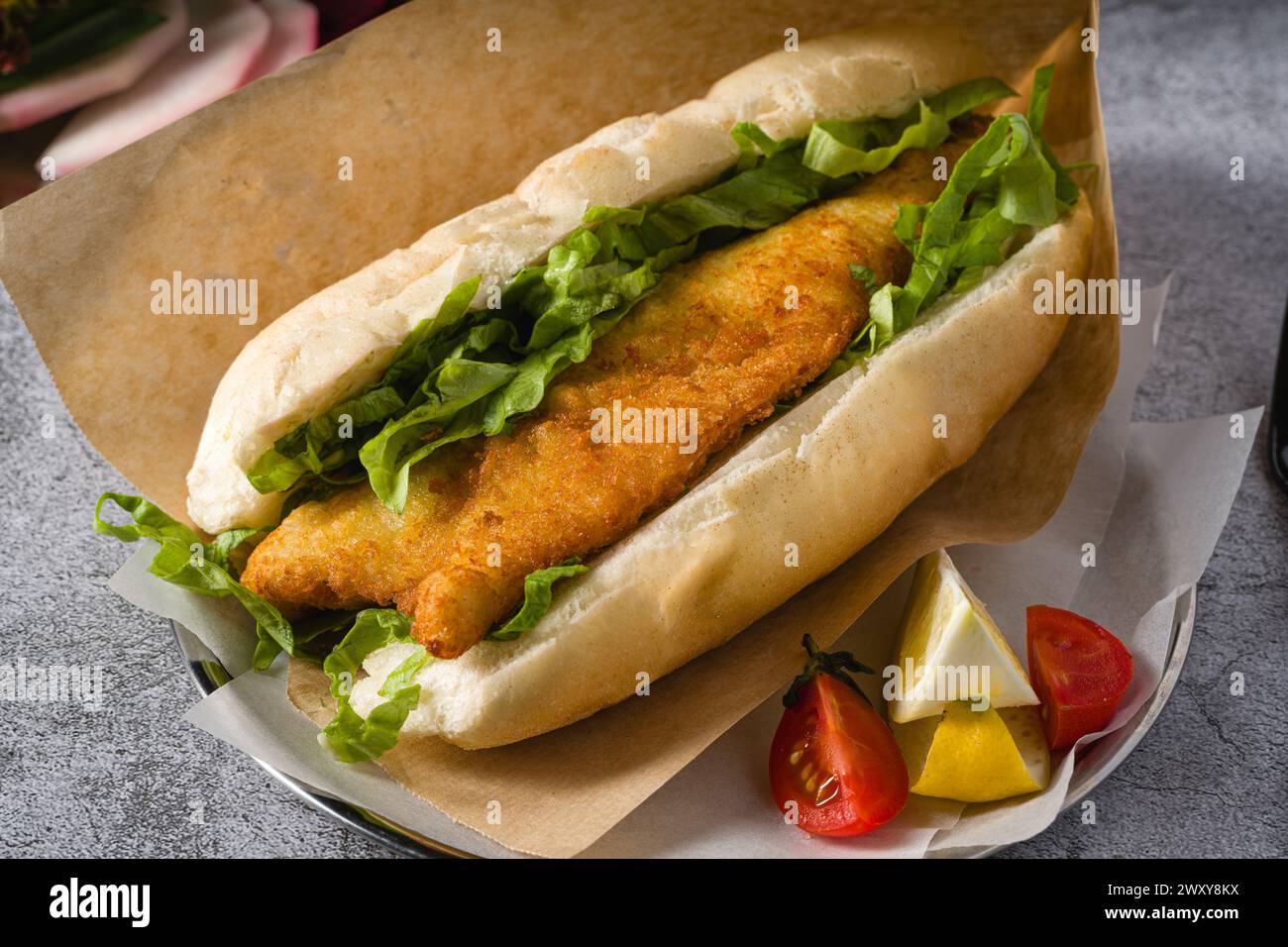 Gebratenes Fisch-Sandwich mit Gemüse auf dem Steintisch. Türkischer Name Balik Ekmek Stockfoto