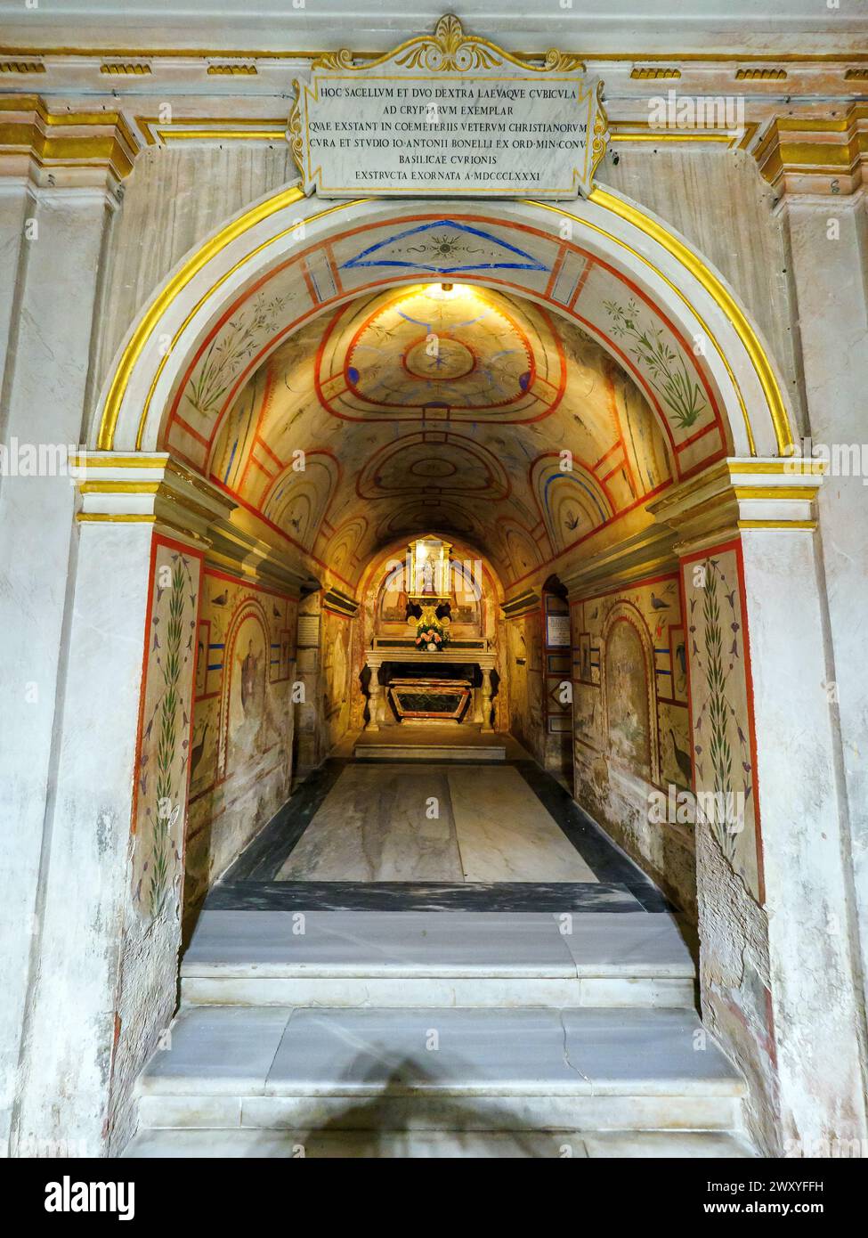 Die gewaltige Krypta unter dem Hauptaltar, die von Luigi Carimini 1869-71 erbaut wurde und neben den Überresten der Titularapostel Philipp und Jakobus auch die Reliquien verschiedener anderer Märtyrer, die bei diesen Ausgrabungen ans Licht kamen, vereint. und die Gräber von zwei Riario, die einst das Recht hatten, im Presbyterium zu begraben. Die Tempera-Dekoration des Ambulatoriums ist von den Katakomben von San Callisto und Domitilla inspiriert. - Basilica dei Santi XII Apostoli - Rom Italien Stockfoto