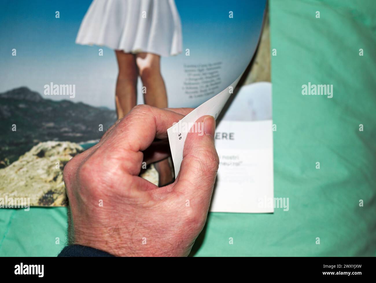 Männliche Hand, die die Seite einer illustrierten Zeitschrift dreht Stockfoto