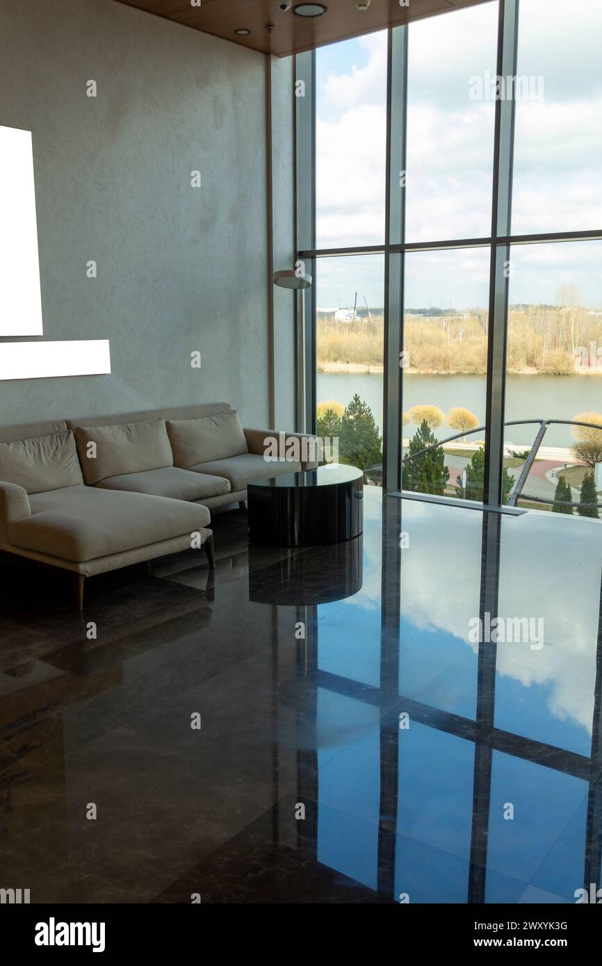 Luxuriöse, komfortable Lounge mit wunderschönem Blick auf die Flussküste, komfortable Couch. Ecksofa vor einem riesigen Fenster in einem modernen Hotel. Stockfoto