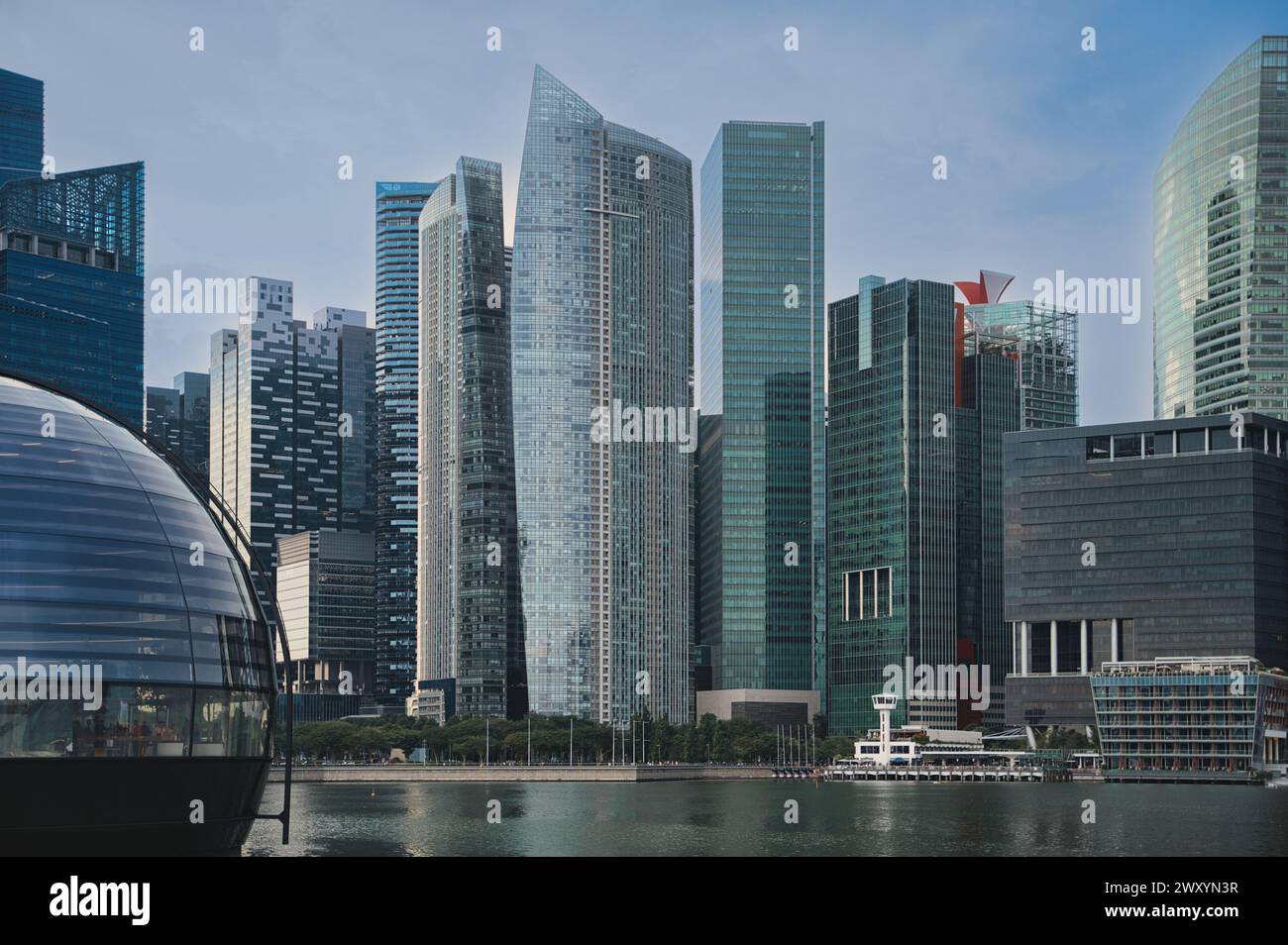 Moderne Wolkenkratzer dominieren die Skyline über einem urbanen Ufergebiet und zeigen die Verschmelzung von Architektur und Wasserstraße Stockfoto
