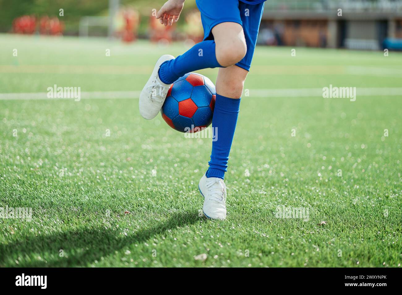 Ein Fußballspieler in blauer Kleidung demonstriert die Ballkontrolle mit seinem Fuß auf einem üppig grünen Fußballfeld Stockfoto