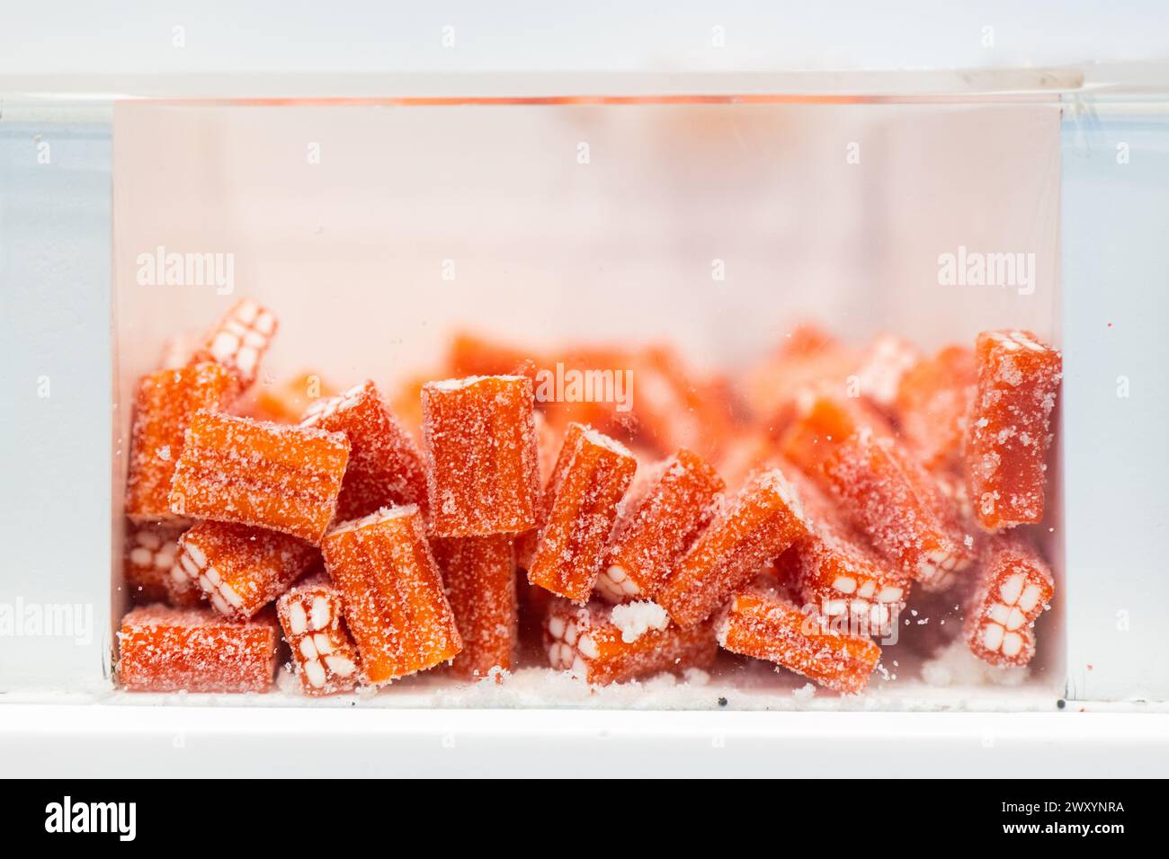 Nahaufnahme von saftigen, mit Granulat überzogenen Süßigkeiten mit Orangengeschmack, in einem transparenten Glas Stockfoto