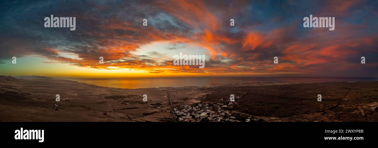 Panoramablick auf Fuerteventuras zerklüftete Landschaft, ein beliebtes Surfziel mit dramatischem Himmel, der sich im Atlantischen Ozean spiegelt. Stockfoto